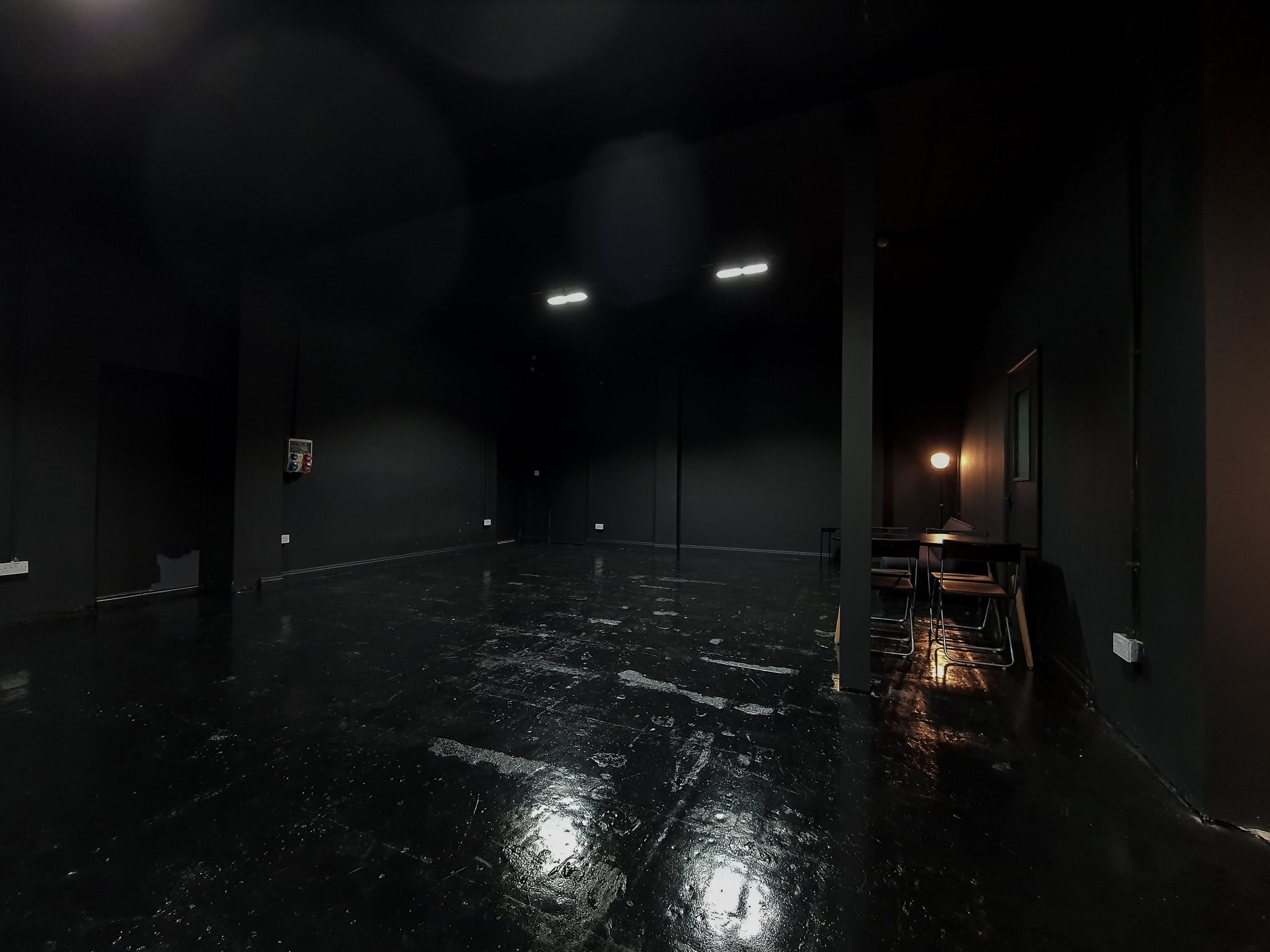 Versatile minimalist event space with dark walls, ideal for workshops and private events.