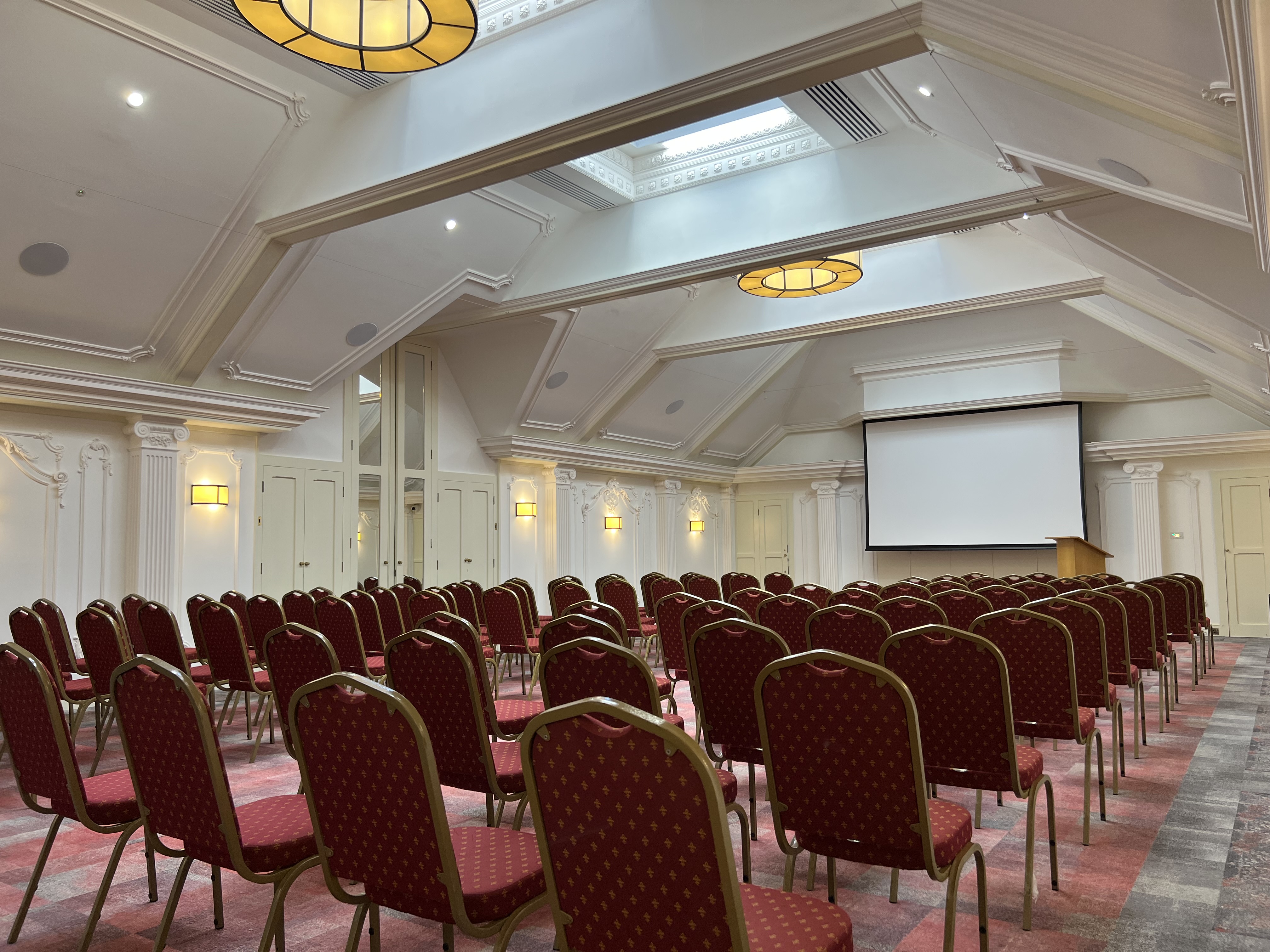 London Room at Warren House Hotel with tiered red seating for conferences and workshops.