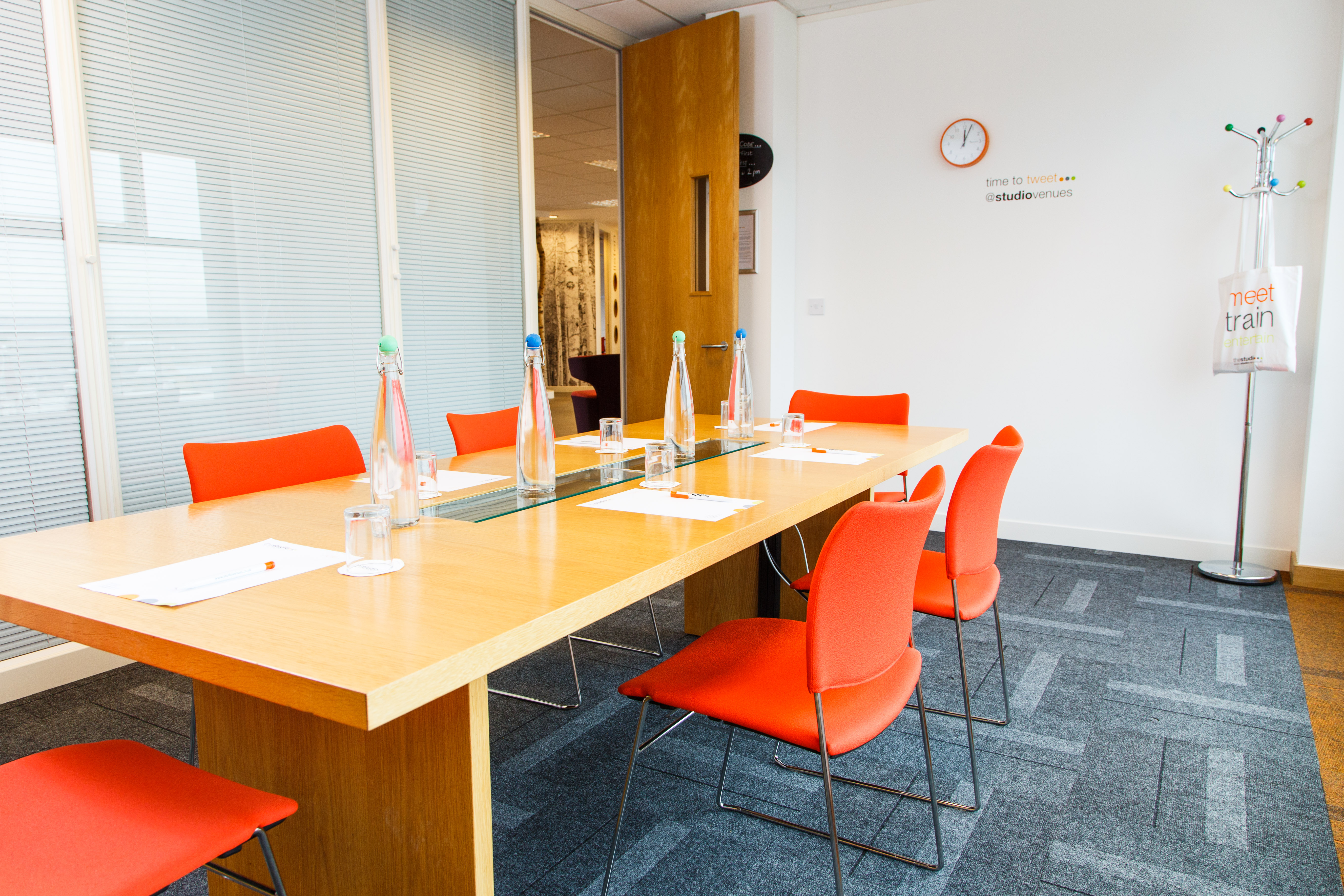 Modern meeting room in Leeds with wooden table and vibrant orange chairs for collaboration.