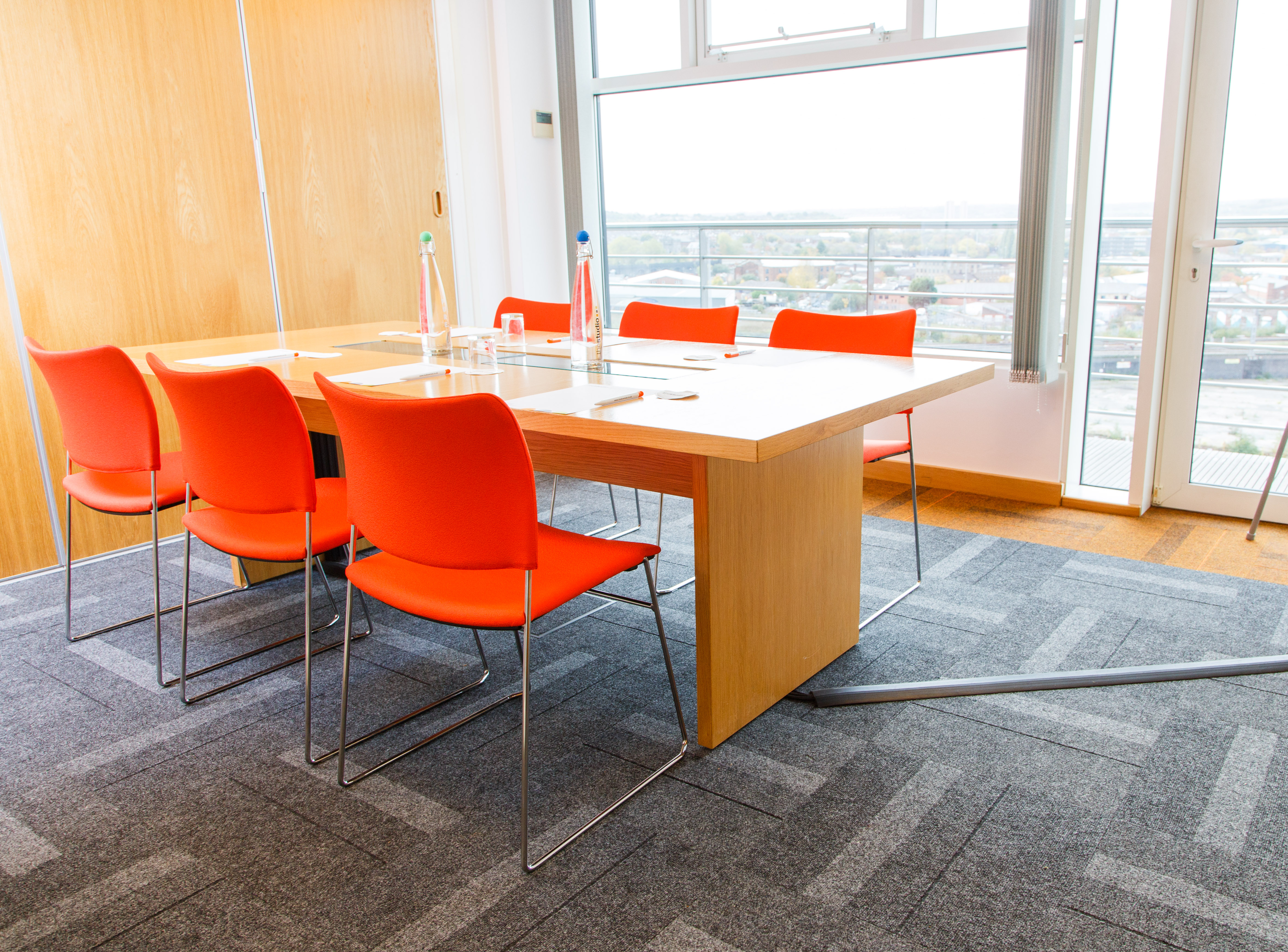 Modern meeting room in Leeds with wooden table and orange chairs for creative collaboration.