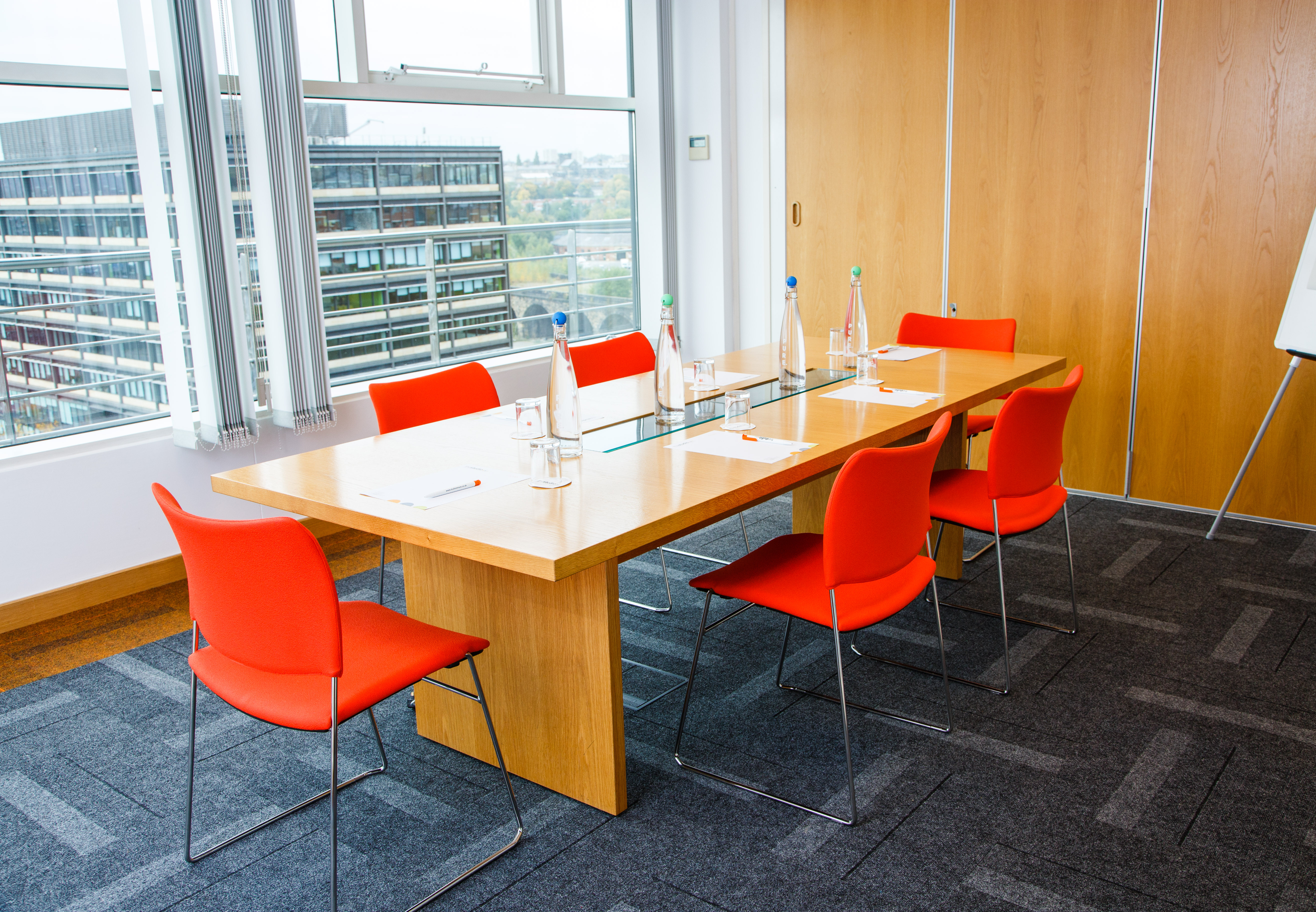 Modern meeting room with wooden table and red chairs for productive brainstorming sessions.