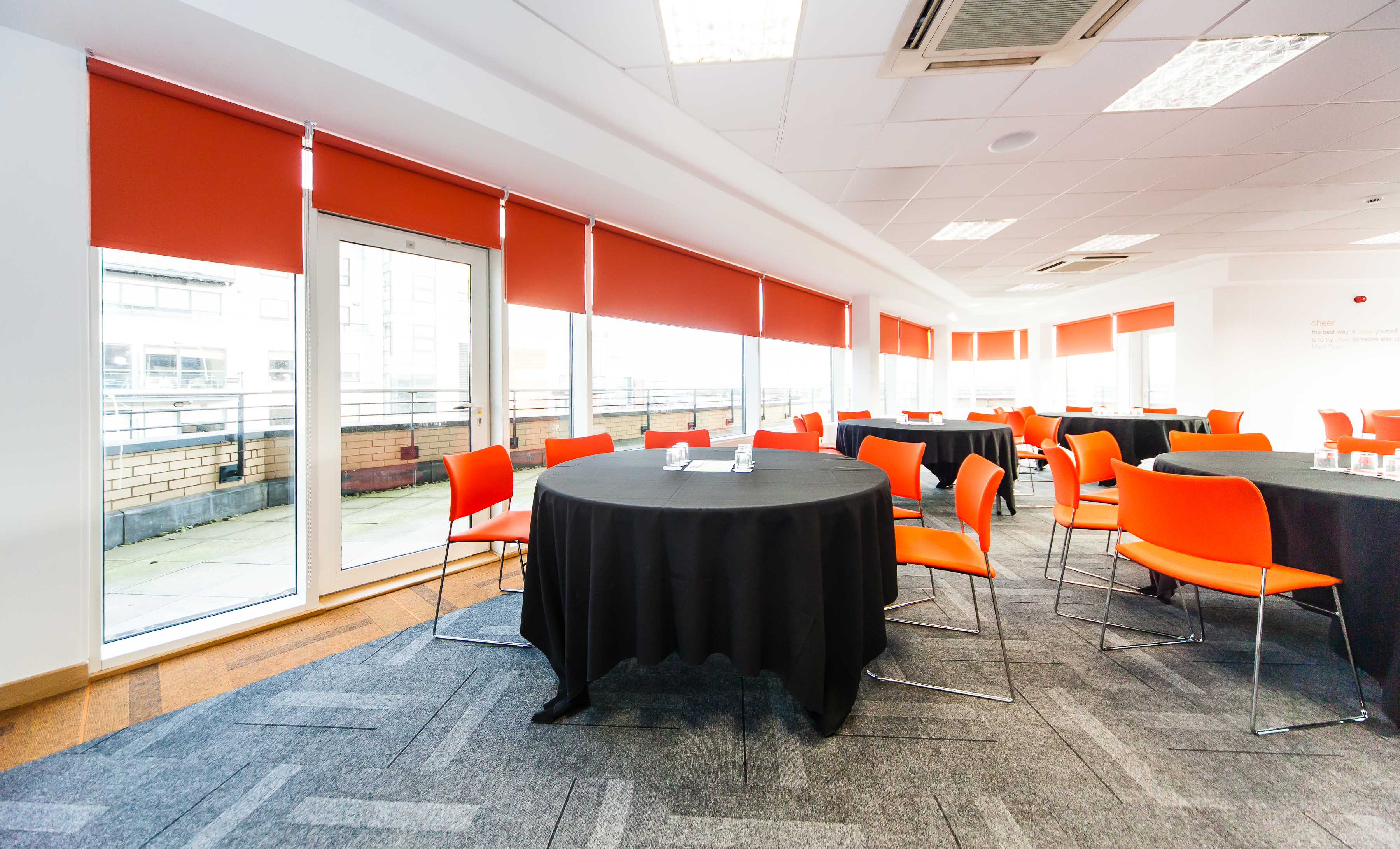 Modern meeting space in Leeds with round tables and vibrant orange chairs for events.