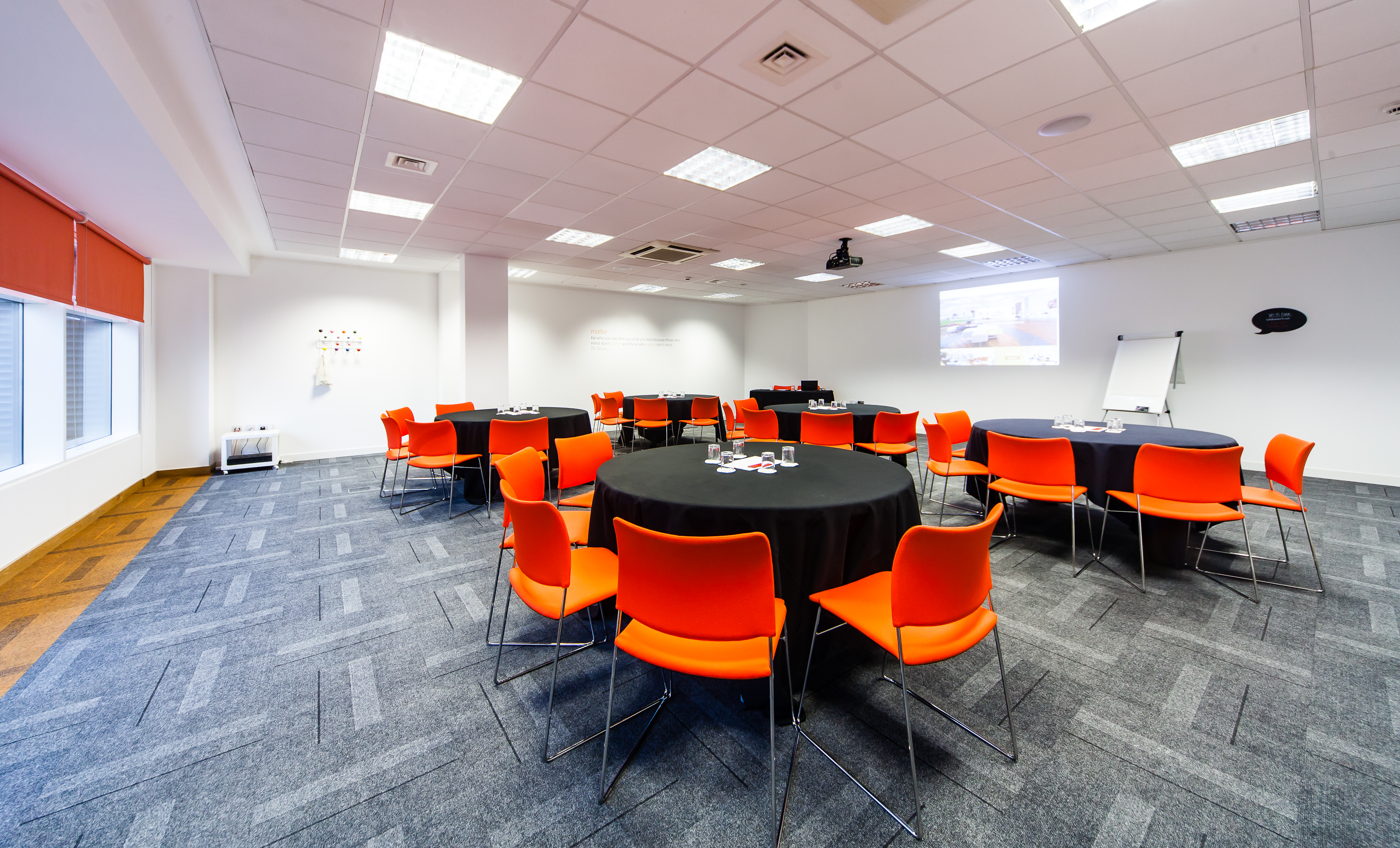 Modern meeting space with round tables, orange chairs for workshops and conferences.