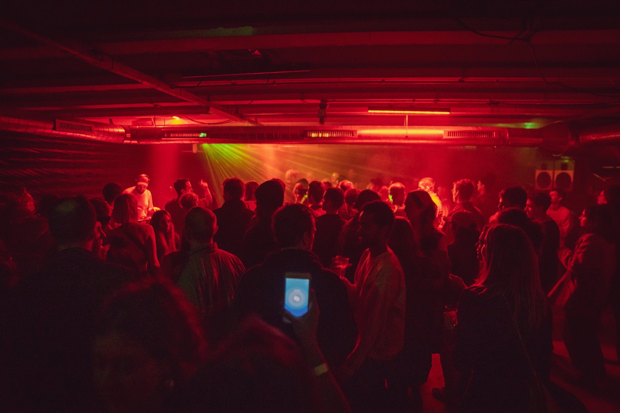 Vibrant event atmosphere in Strange Brew's back room with dynamic red lighting.
