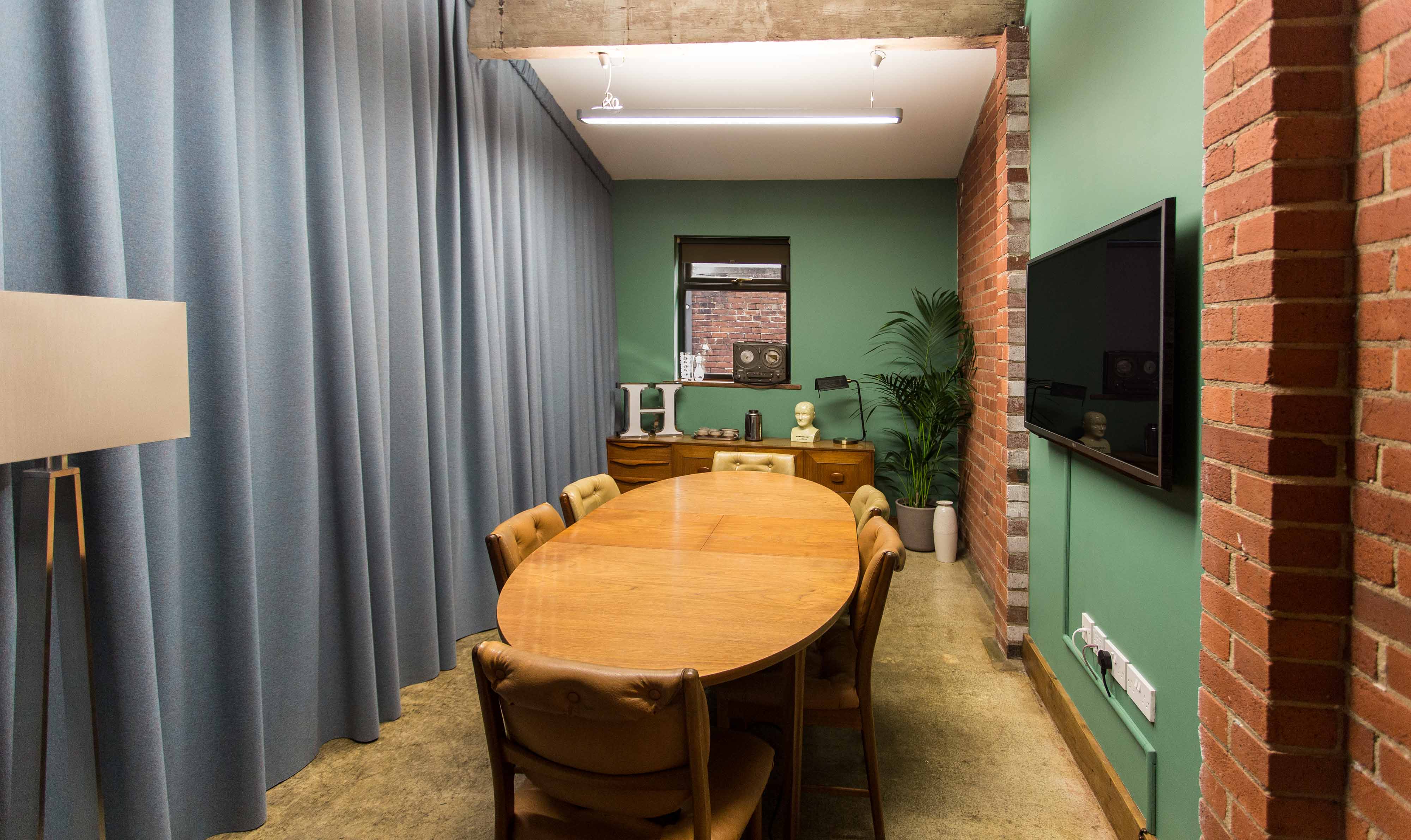 Modern meeting space with warm wood table, ideal for intimate gatherings and brainstorming sessions.