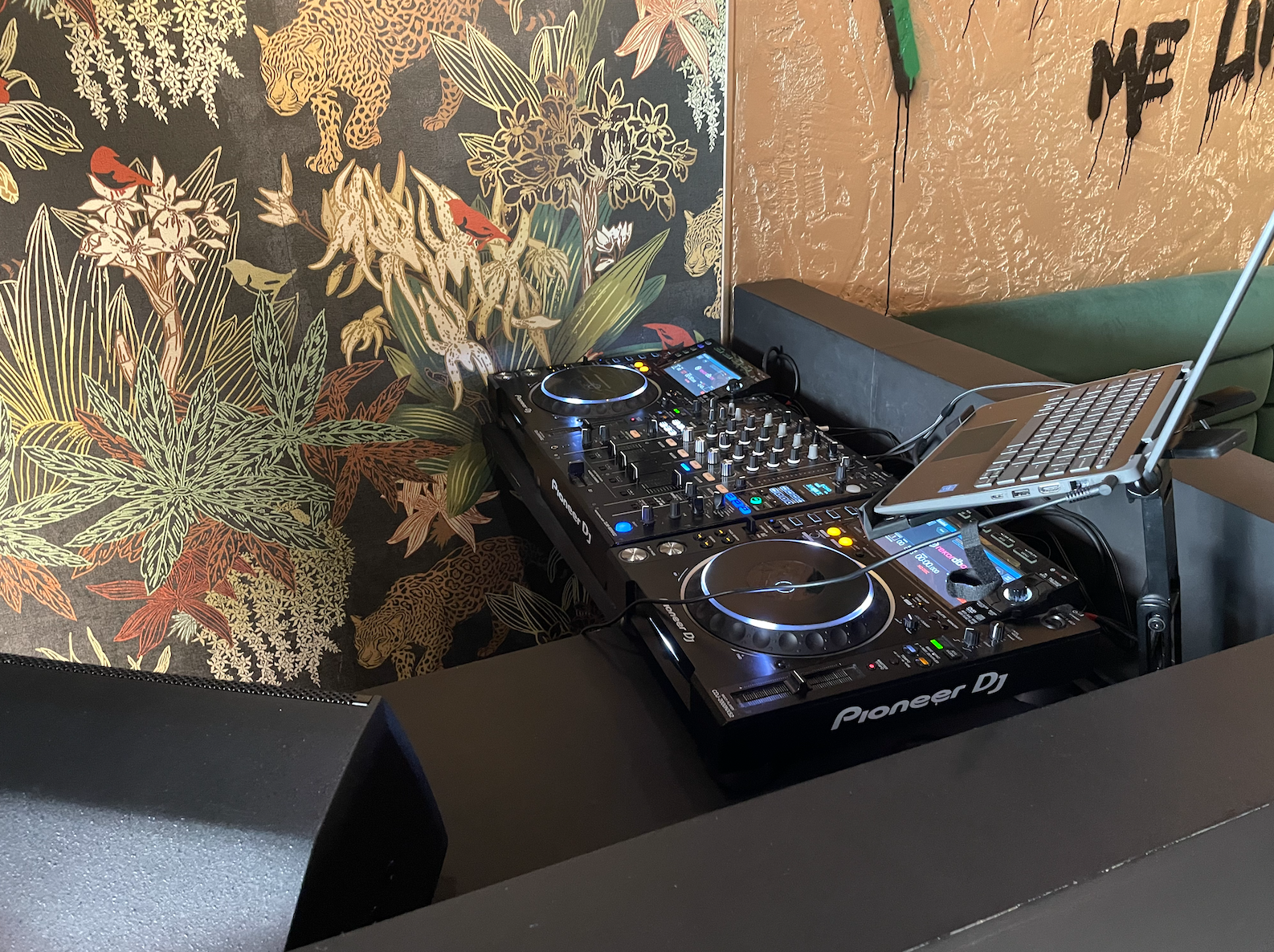 DJ setup with Pioneer controller in vibrant tropical-themed event space.
