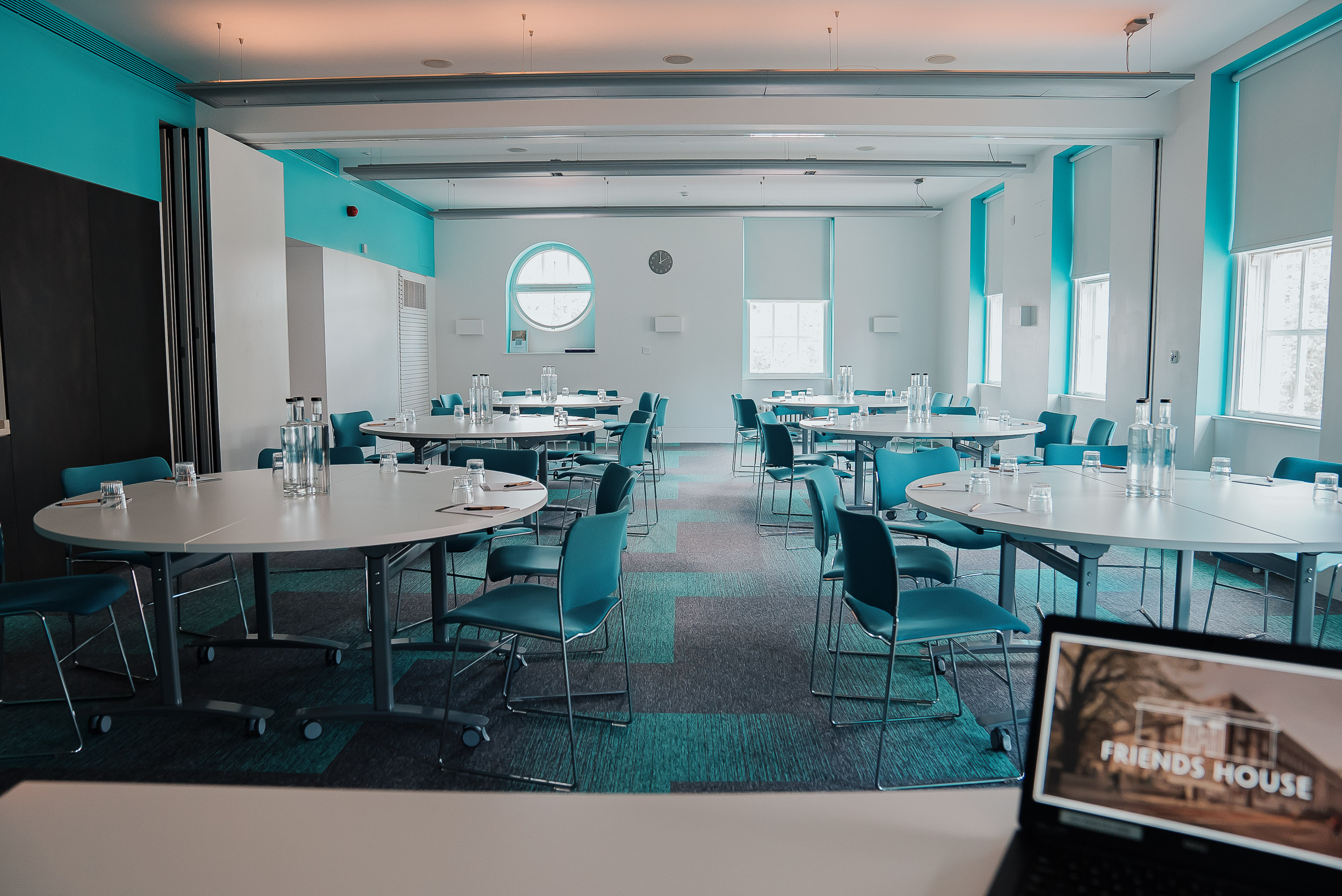 Meeting room with round tables and blue accents for workshops or seminars.