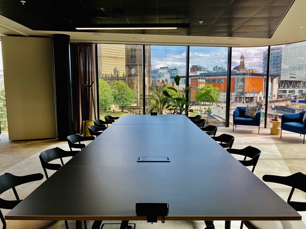 Modern meeting room with a long black table and large windows for inspired discussions.