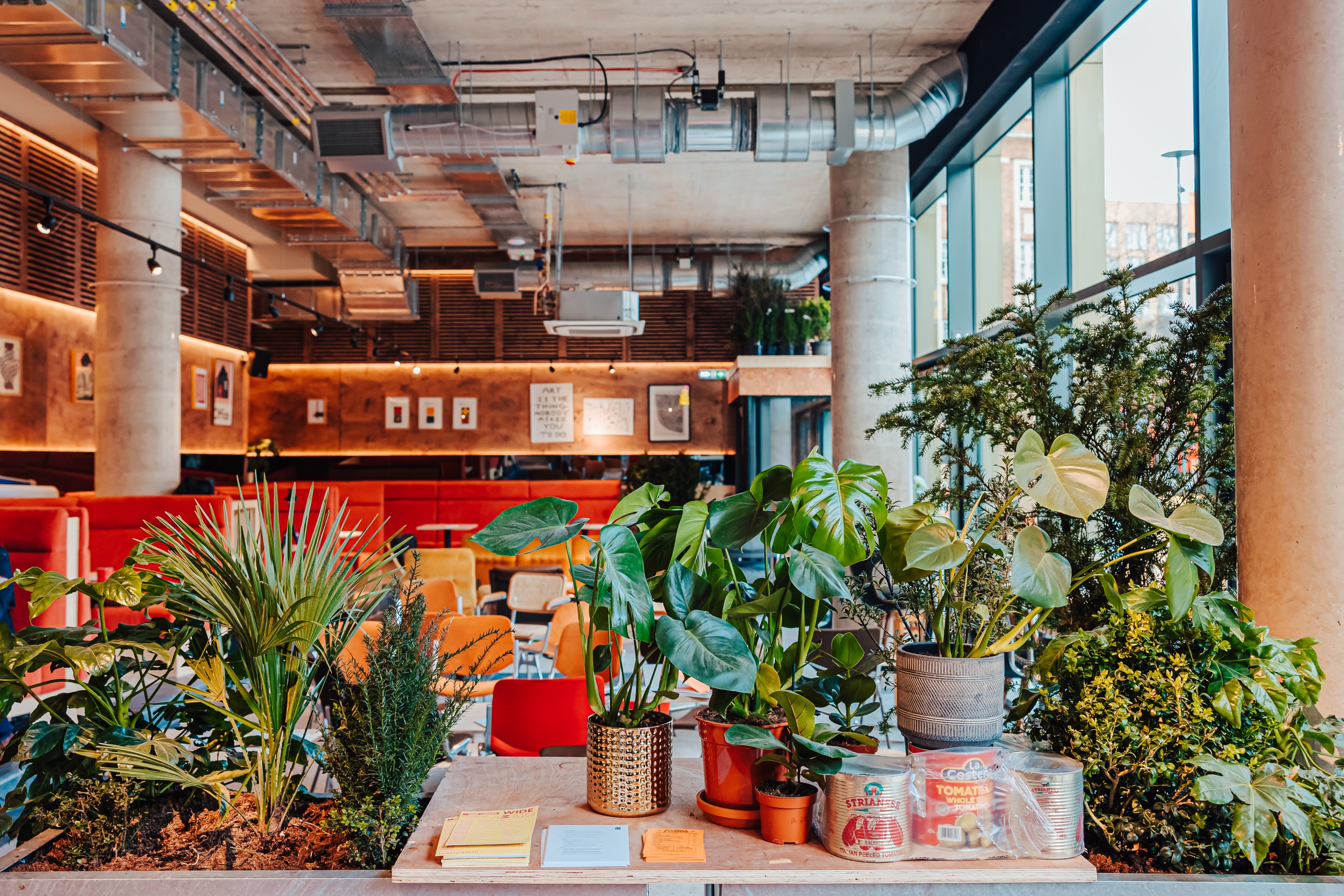 Vibrant Mezzanine event space with lush greenery for networking and meetings.
