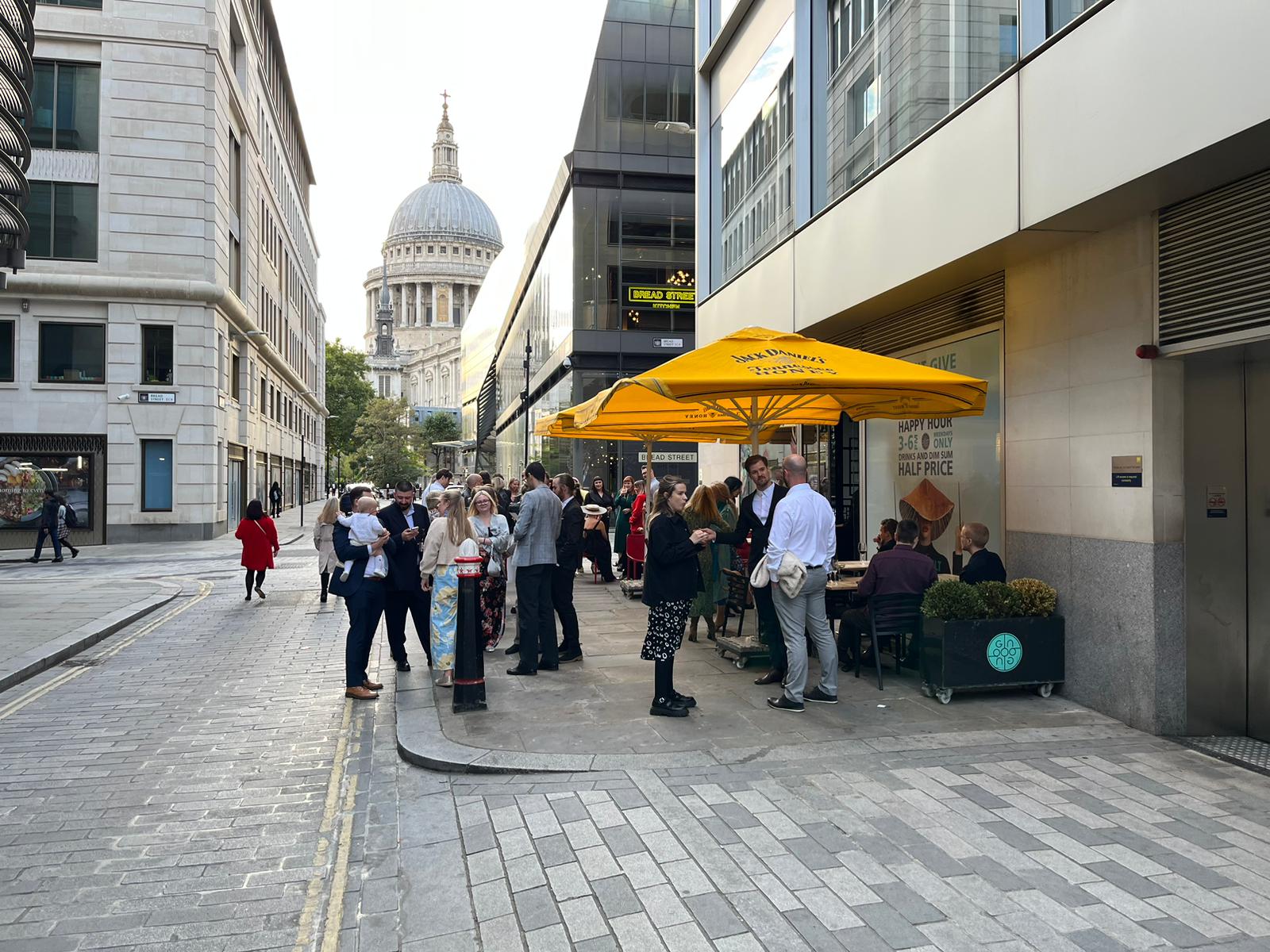 Outdoor networking event at Ping Pong Bow Bell's House with yellow umbrella and St. Paul's Cathedral.