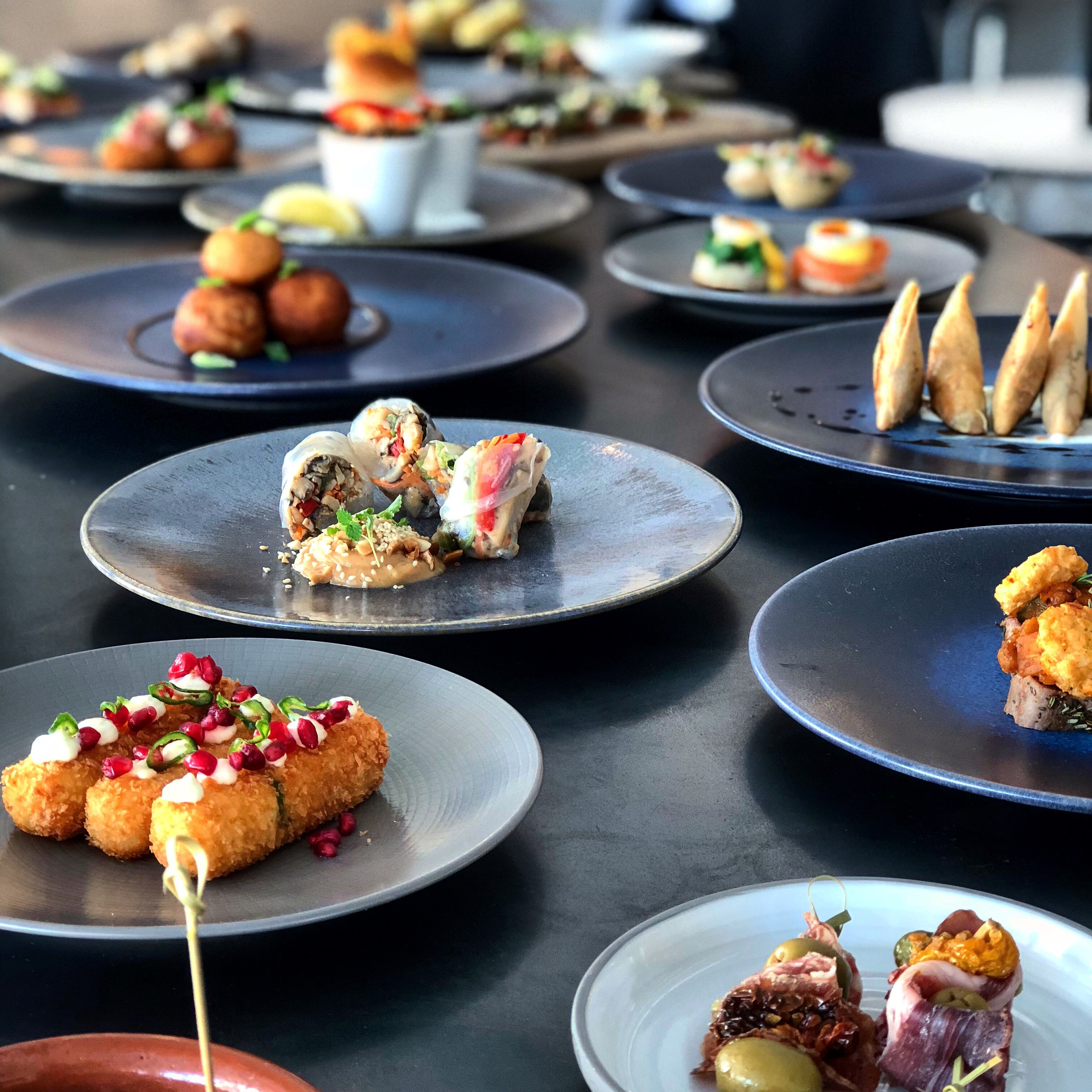 Gourmet appetizers on dark plates at Fourth Floor Bar, Leeds for upscale events.
