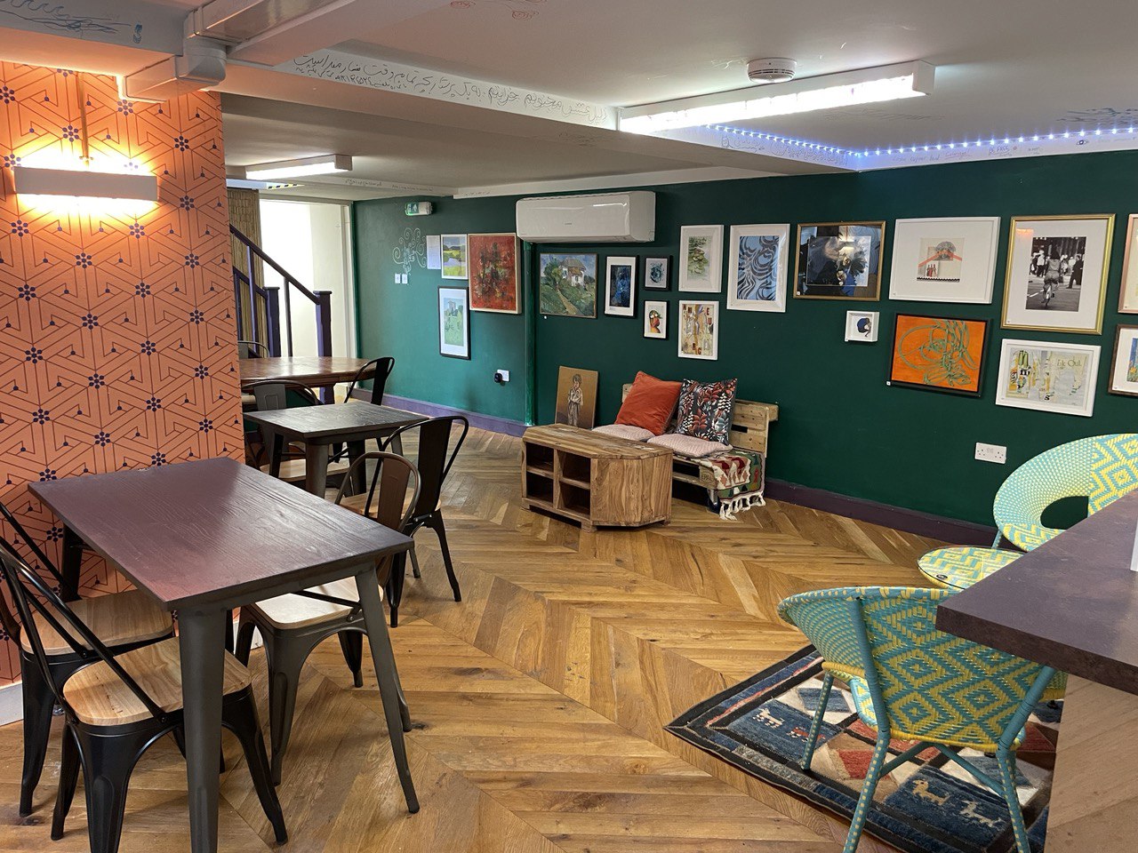 Cozy Geo Art Cafe meeting space with wooden furniture and vibrant wall art for workshops.