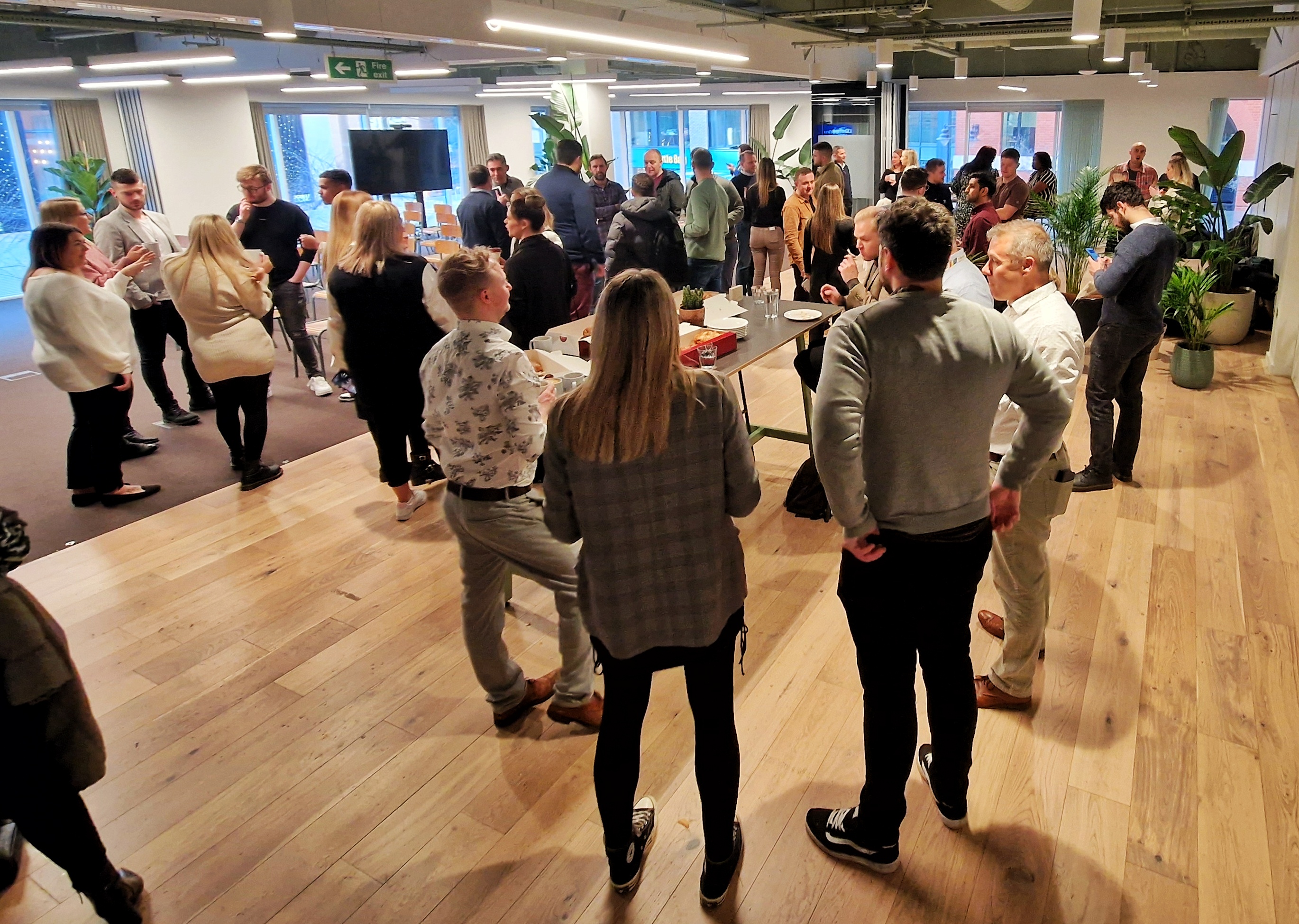 Vibrant networking event in modern Foundry office space with greenery and engaged attendees.