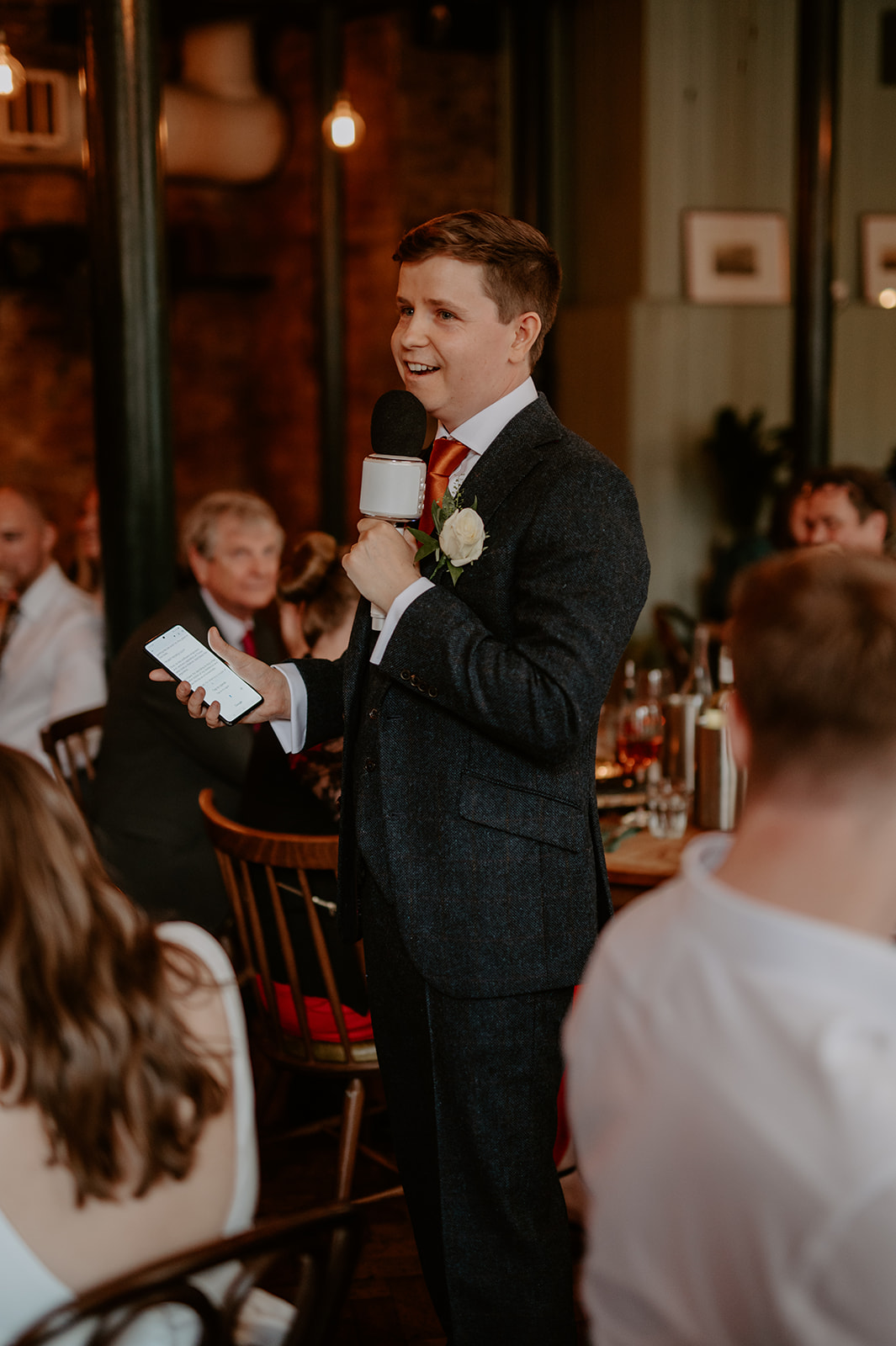 Speaker with microphone at Casa do Frango event, delivering toast to engaged audience.