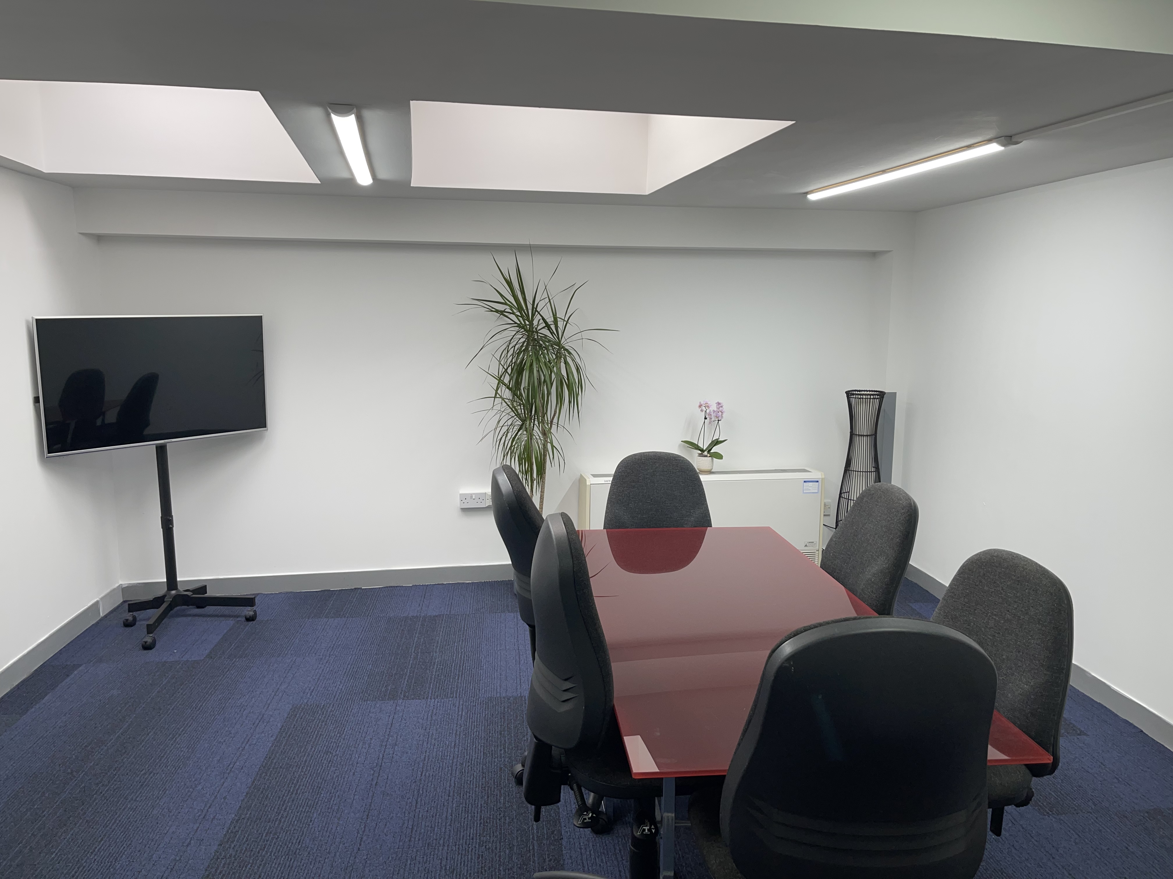 Modern meeting room with red conference table, perfect for brainstorming sessions.