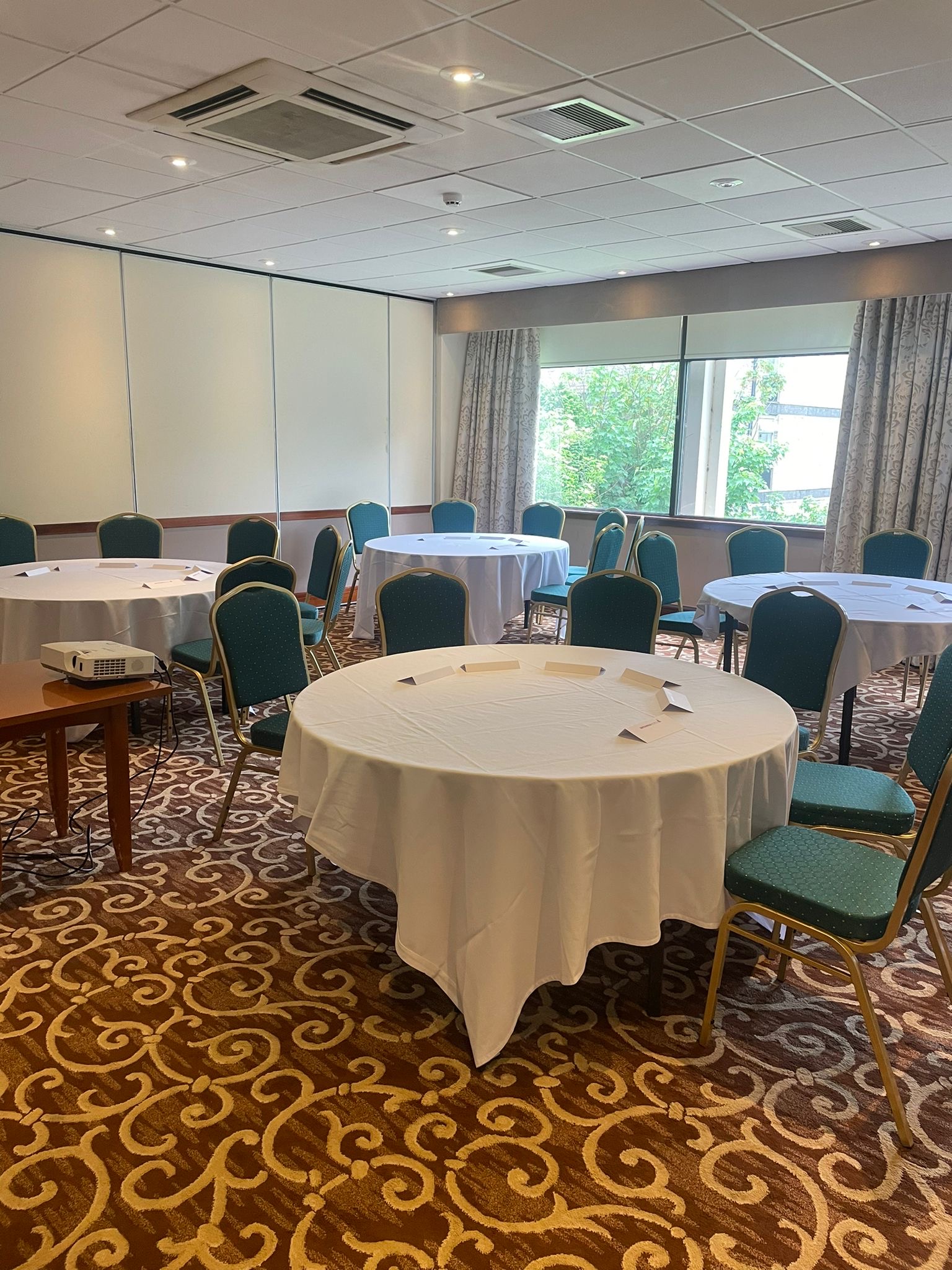 Bright meeting room with round tables at Leeds Bradford Airport Hotel for workshops.
