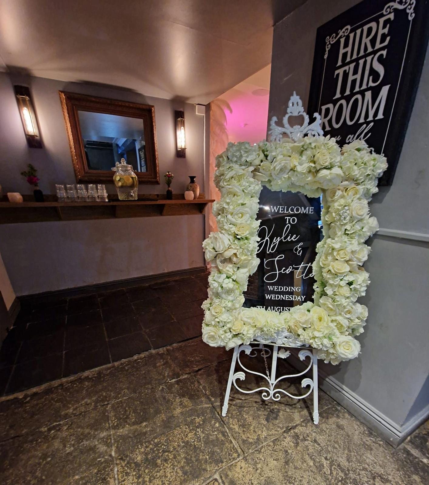 Elegant wedding welcome sign framed by white flowers in romantic garden room.