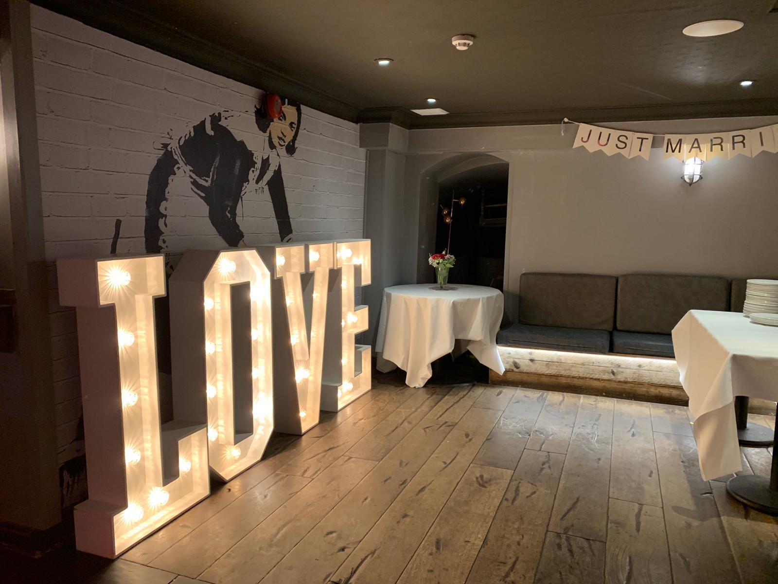 Charming wedding venue with illuminated "LOVE" letters and elegant decor.
