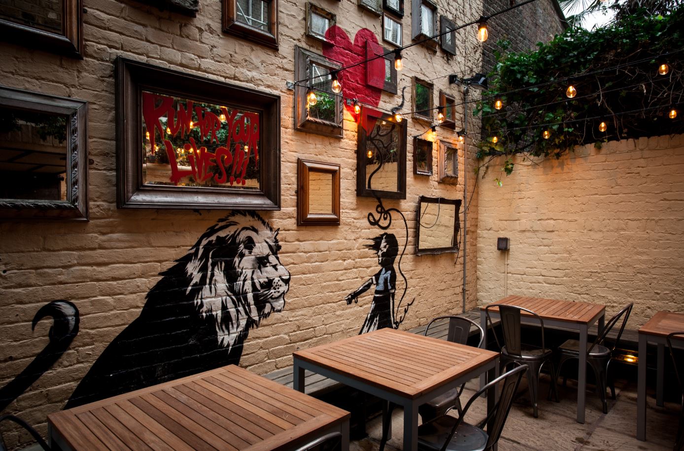 Vibrant garden room with murals and string lights for creative events and gatherings.