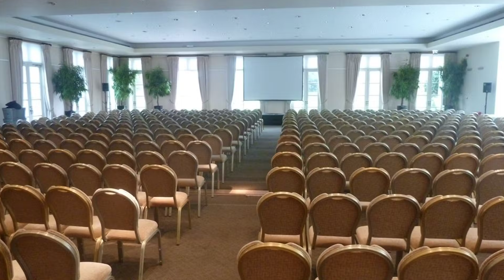 Spacious Palm Court event room with gold chairs for seminars at Hurlingham Club.