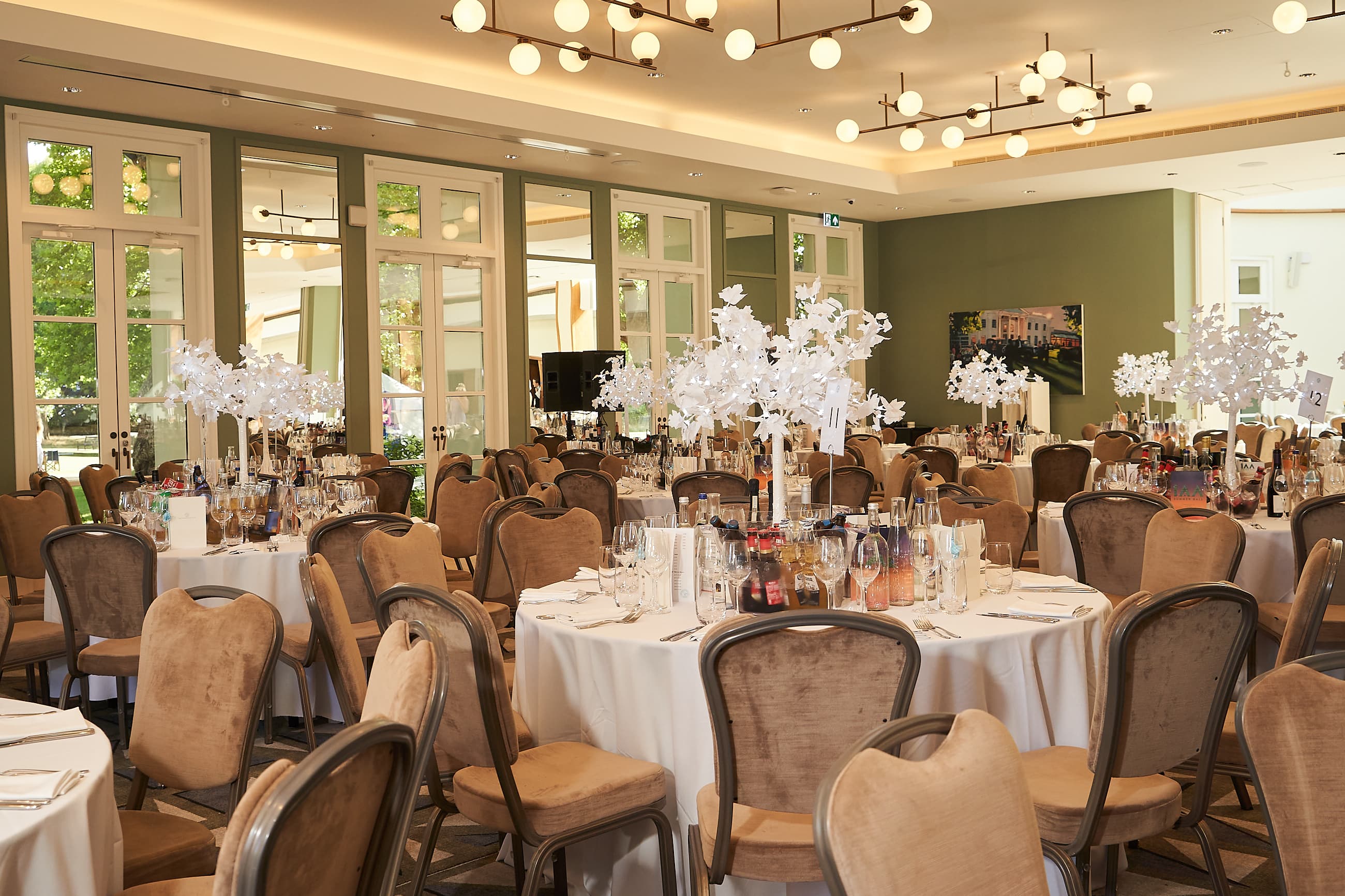 Hurlingham Club ballroom gala dinner setup with sage walls and sculptural centerpieces.