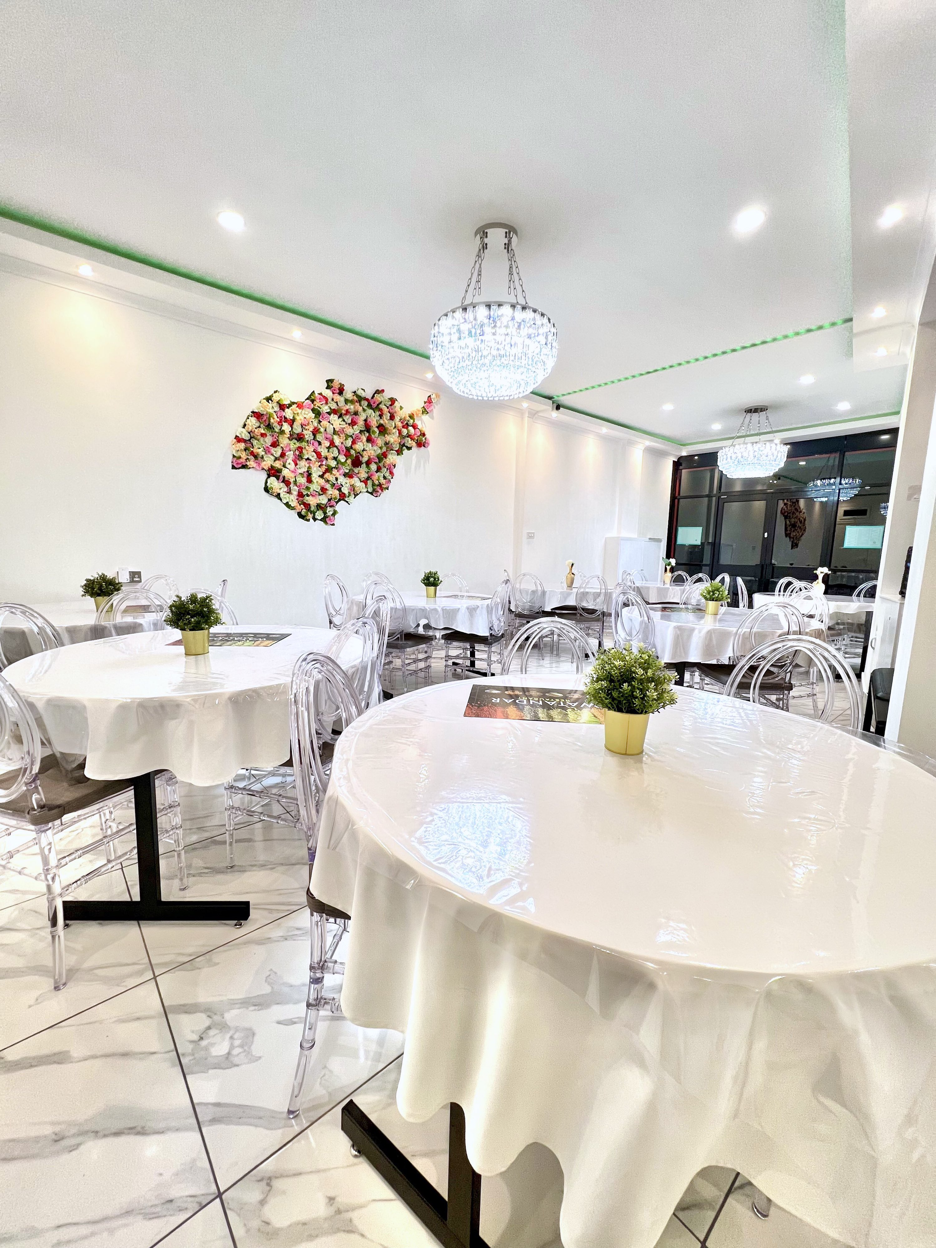Modern event space with round tables and floral wall art, perfect for meetings and celebrations.