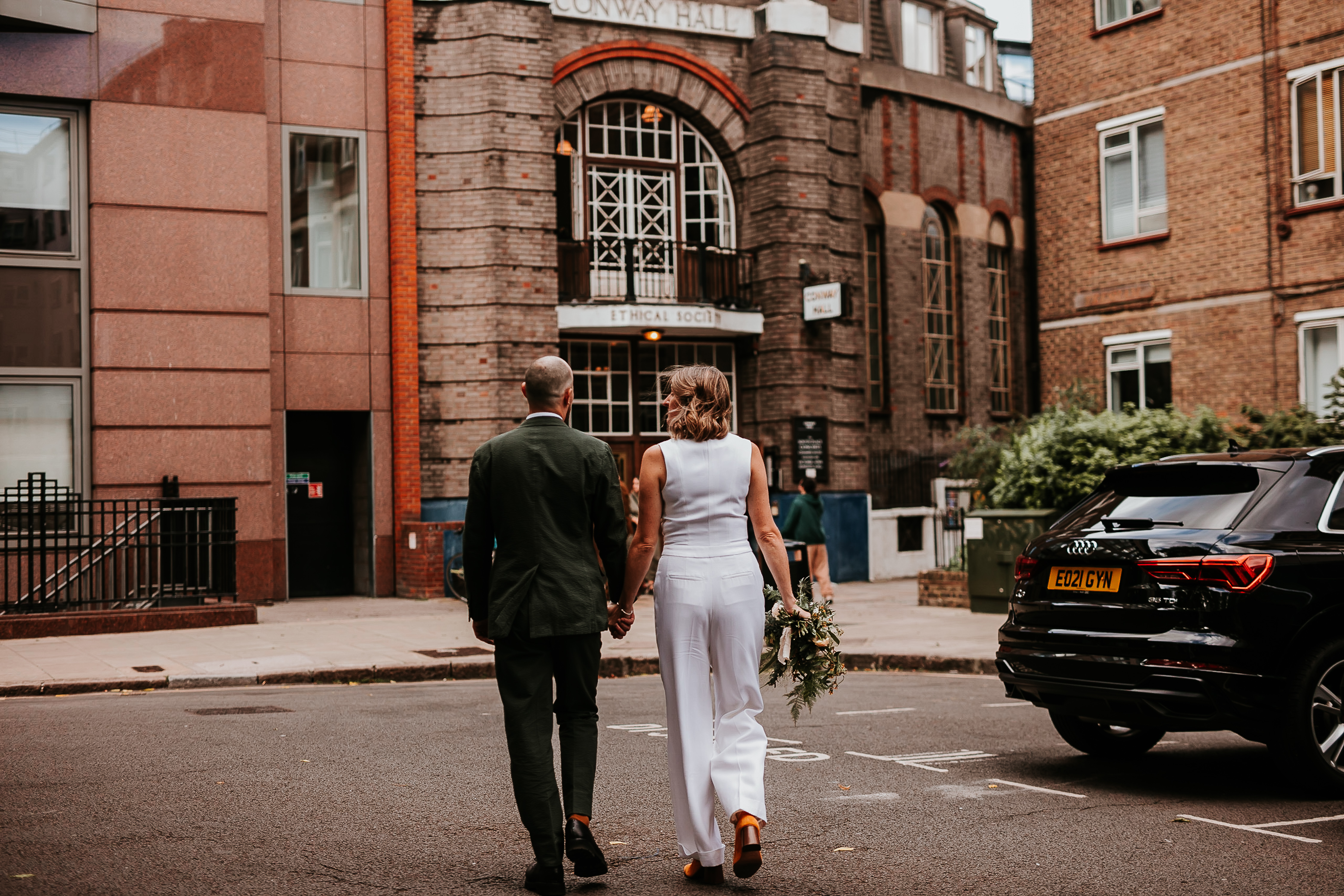 Couple walking hand in hand at elegant Conway Hall wedding venue.