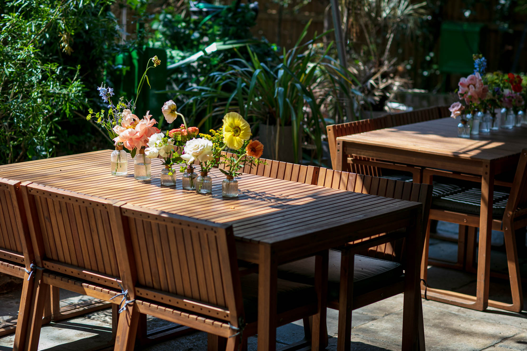 Outdoor event space at God's Garden, featuring wooden tables and vibrant floral centerpieces.