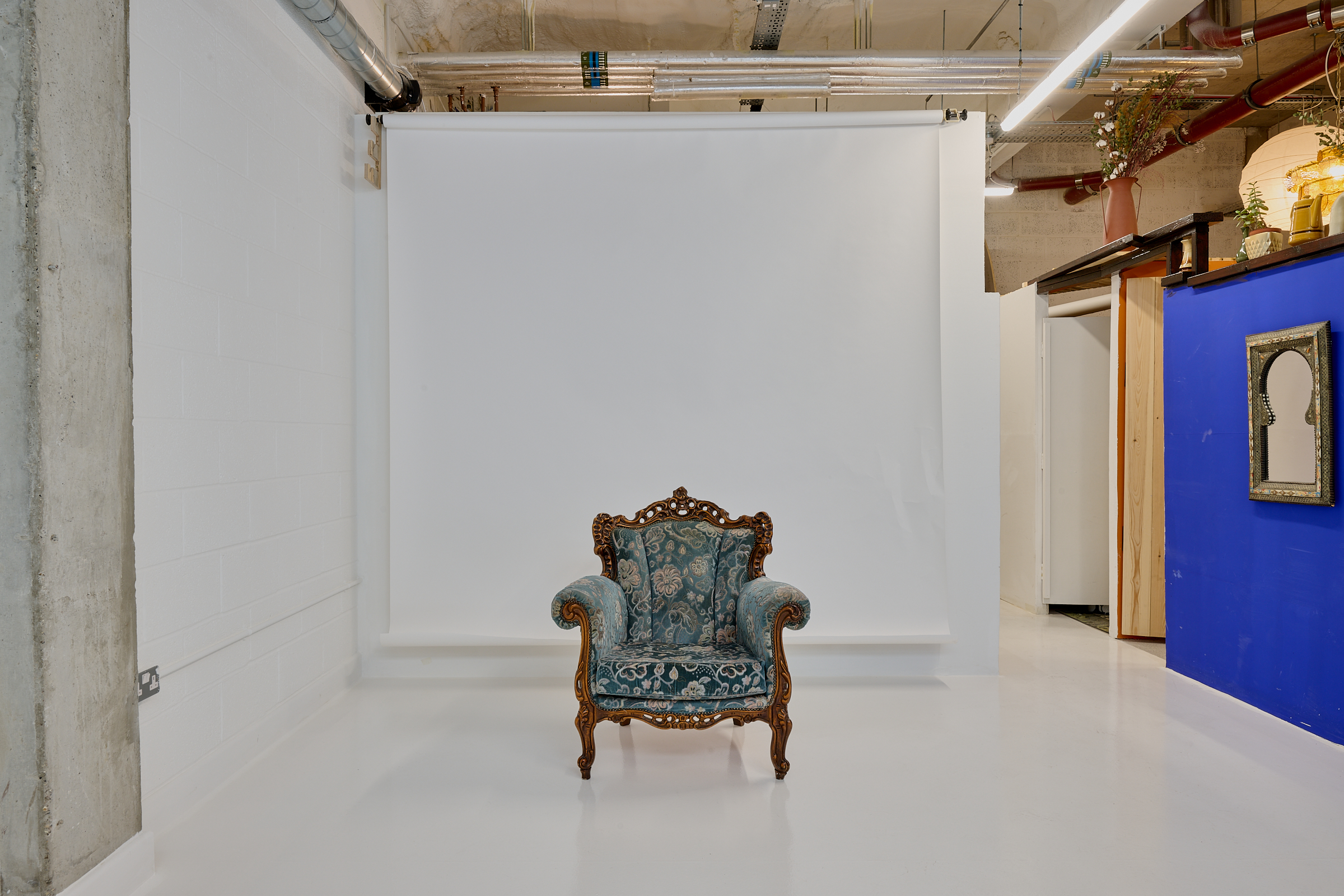 Minimalist event space with vintage armchair, ideal for intimate gatherings and photos.