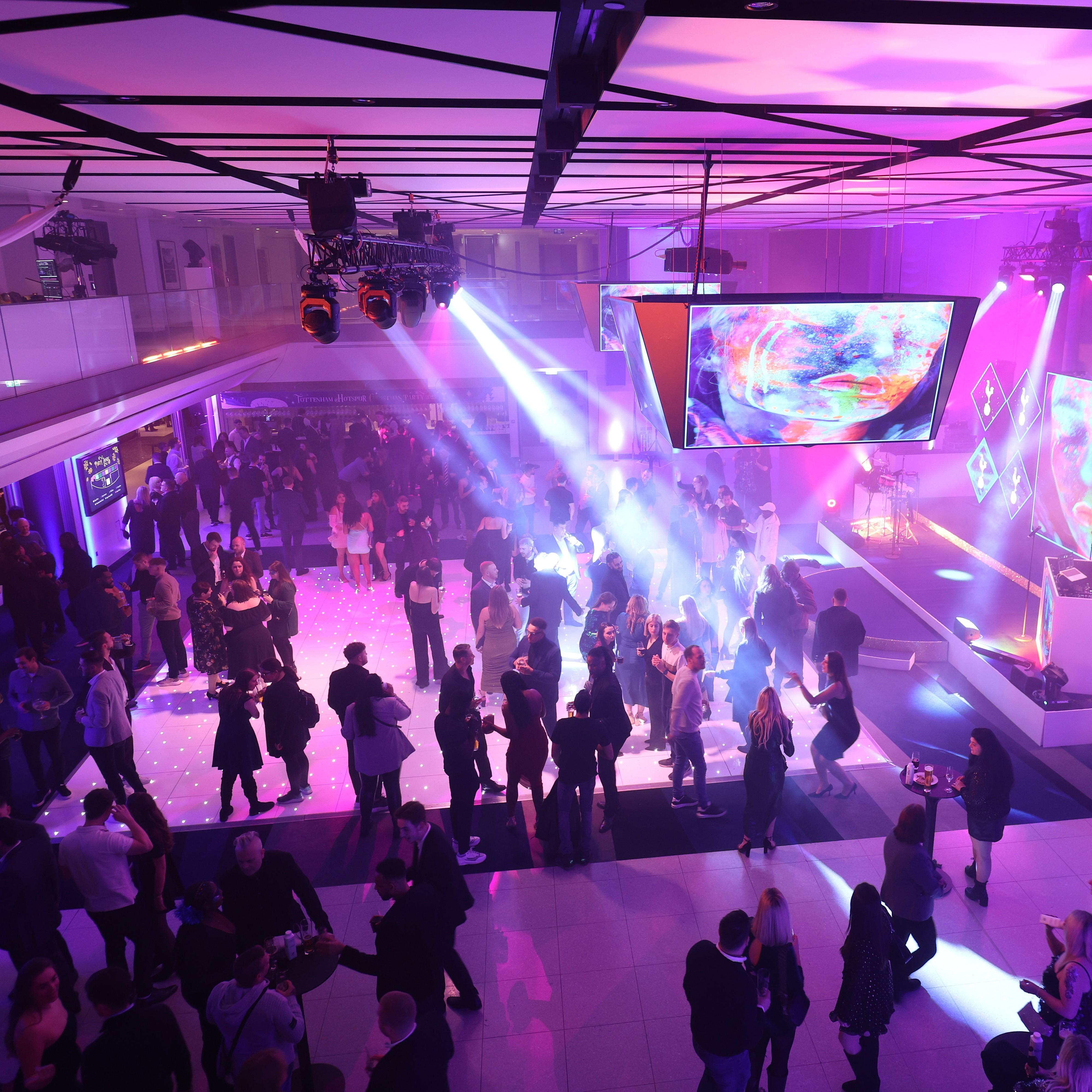 "Christmas party at Tottenham Hotspur Stadium with vibrant lighting and live DJ"