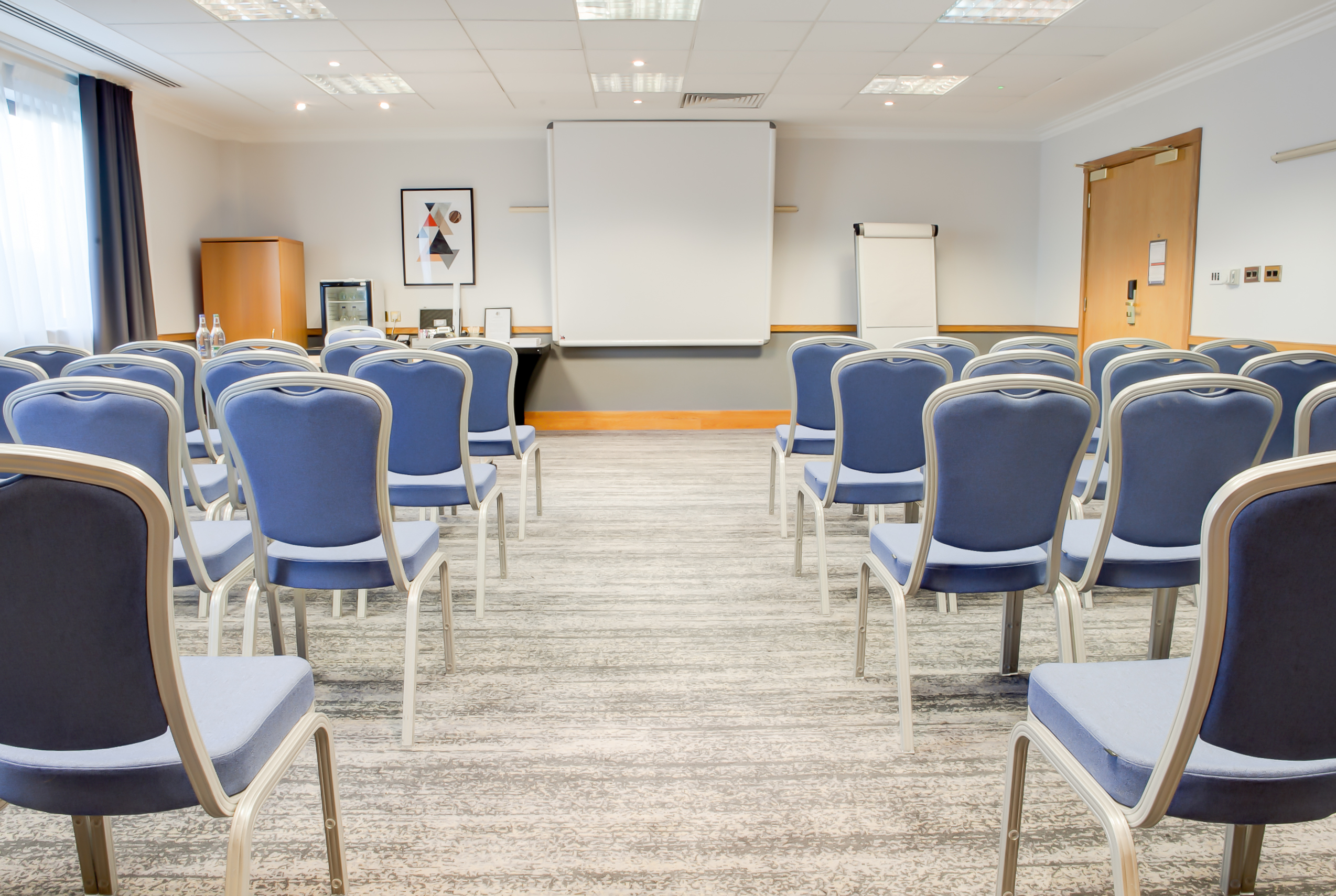 Dean Suite meeting room at DoubleTree Swindon, featuring blue chairs and a projection screen.