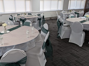 Main Hall event space with elegant round tables and dark green chair sashes for gatherings.