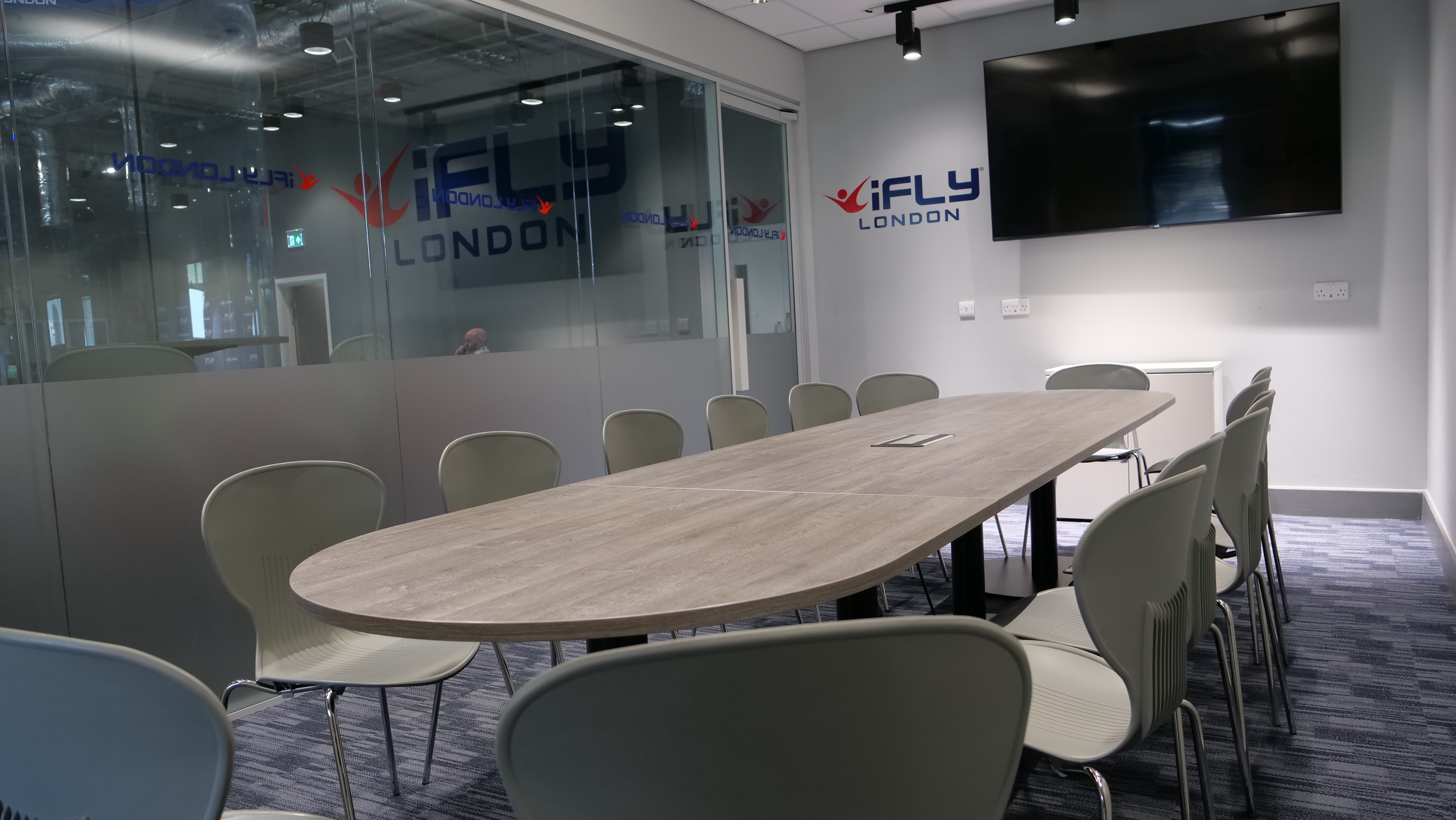 Modern conference room with oval table at iFLY Indoor Skydiving, ideal for corporate events.