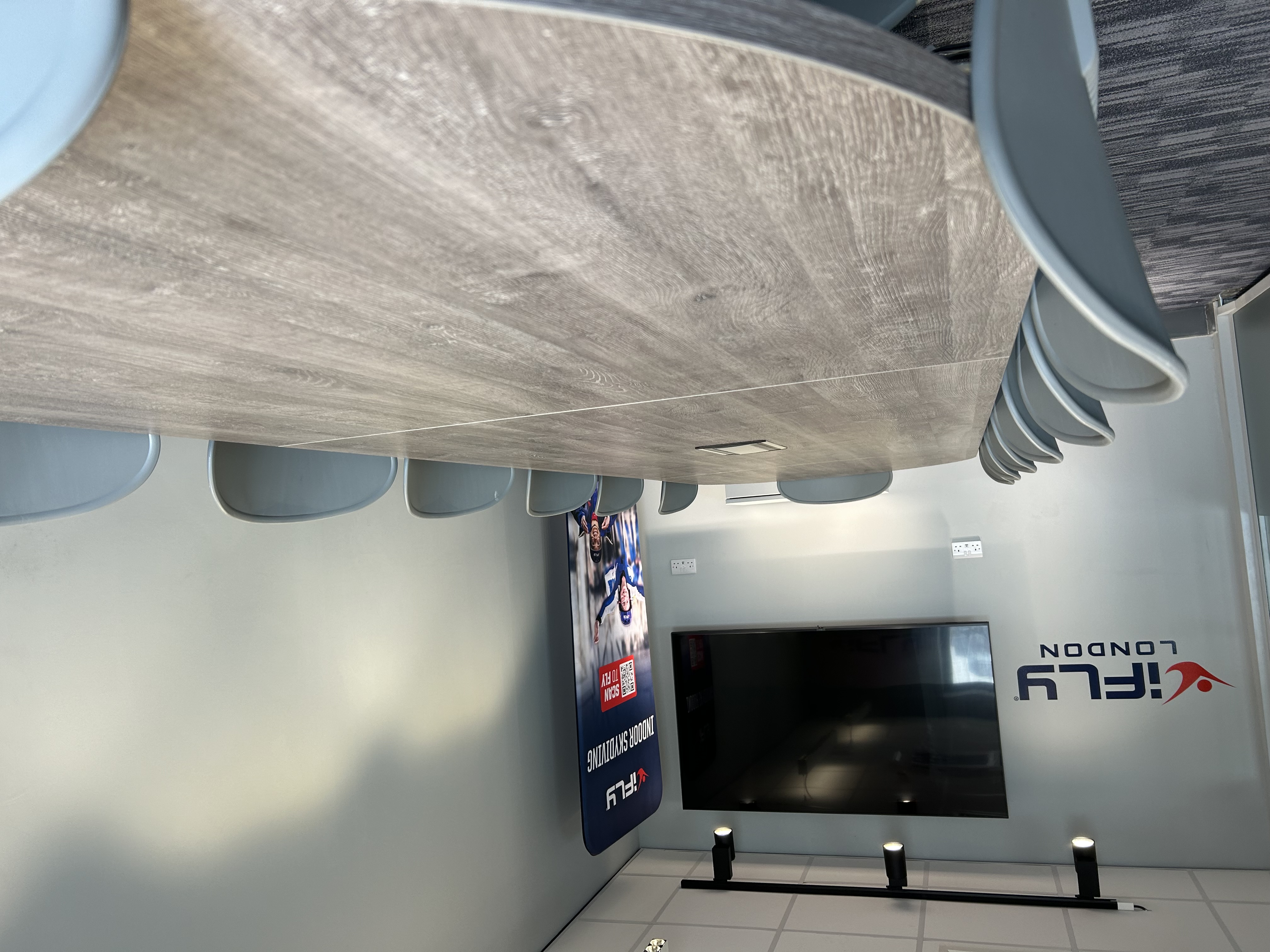Modern conference room with wooden table at iFLY Indoor Skydiving, ideal for corporate events.