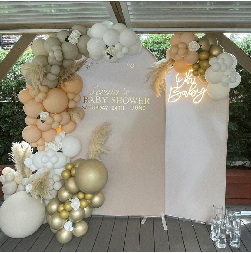 Elegant baby shower backdrop with pastel balloons and pampas grass decor.