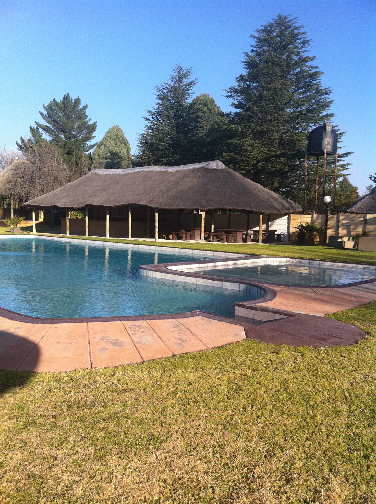Emanzini outdoor venue with thatched roof by pool, ideal for retreats and events.