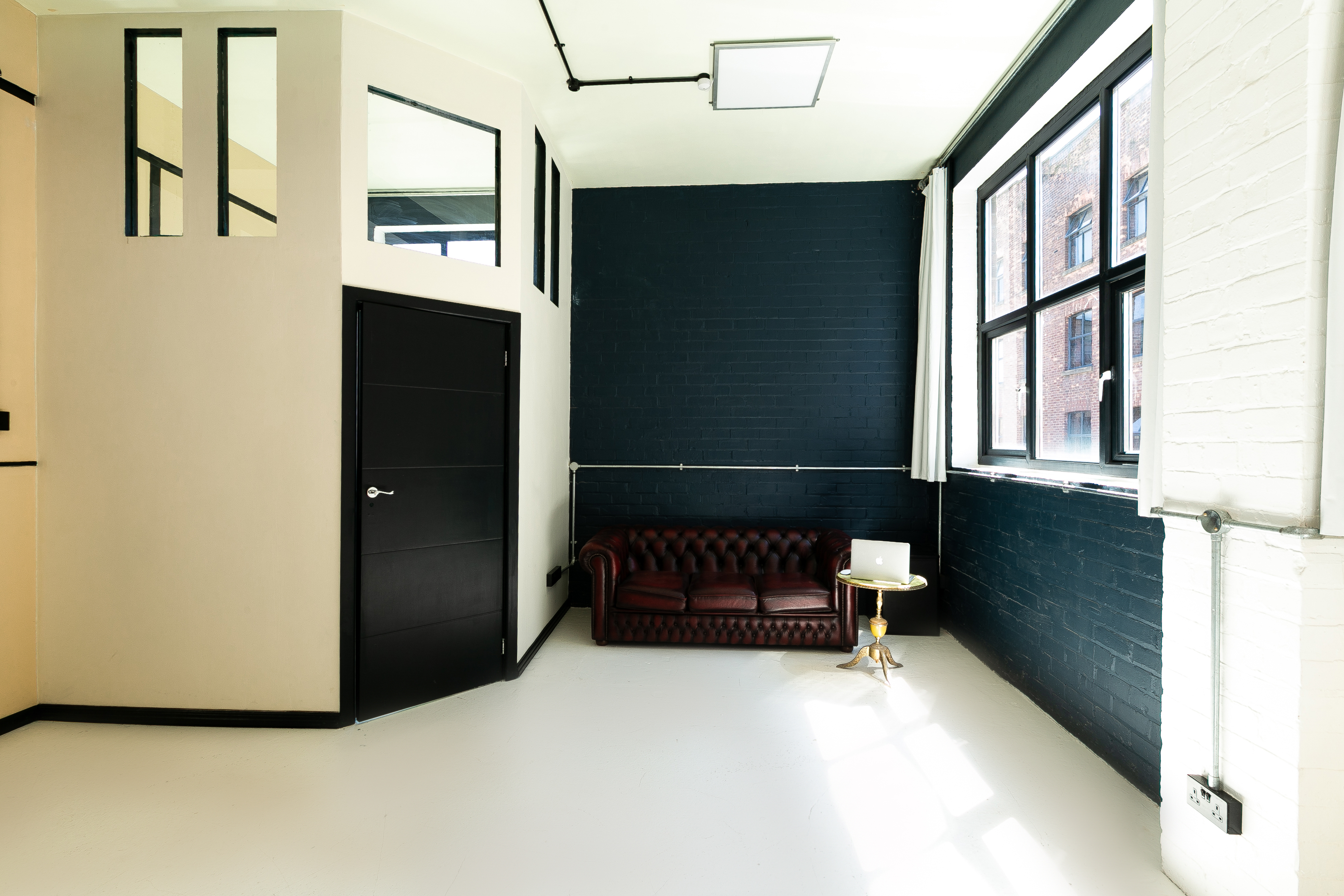 Modern minimalist meeting space with leather couch, ideal for brainstorming and networking.