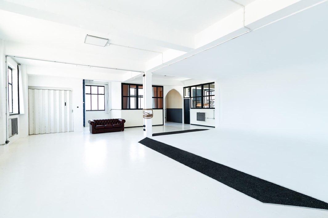 Versatile minimalist event space with natural light for corporate meetings and workshops.