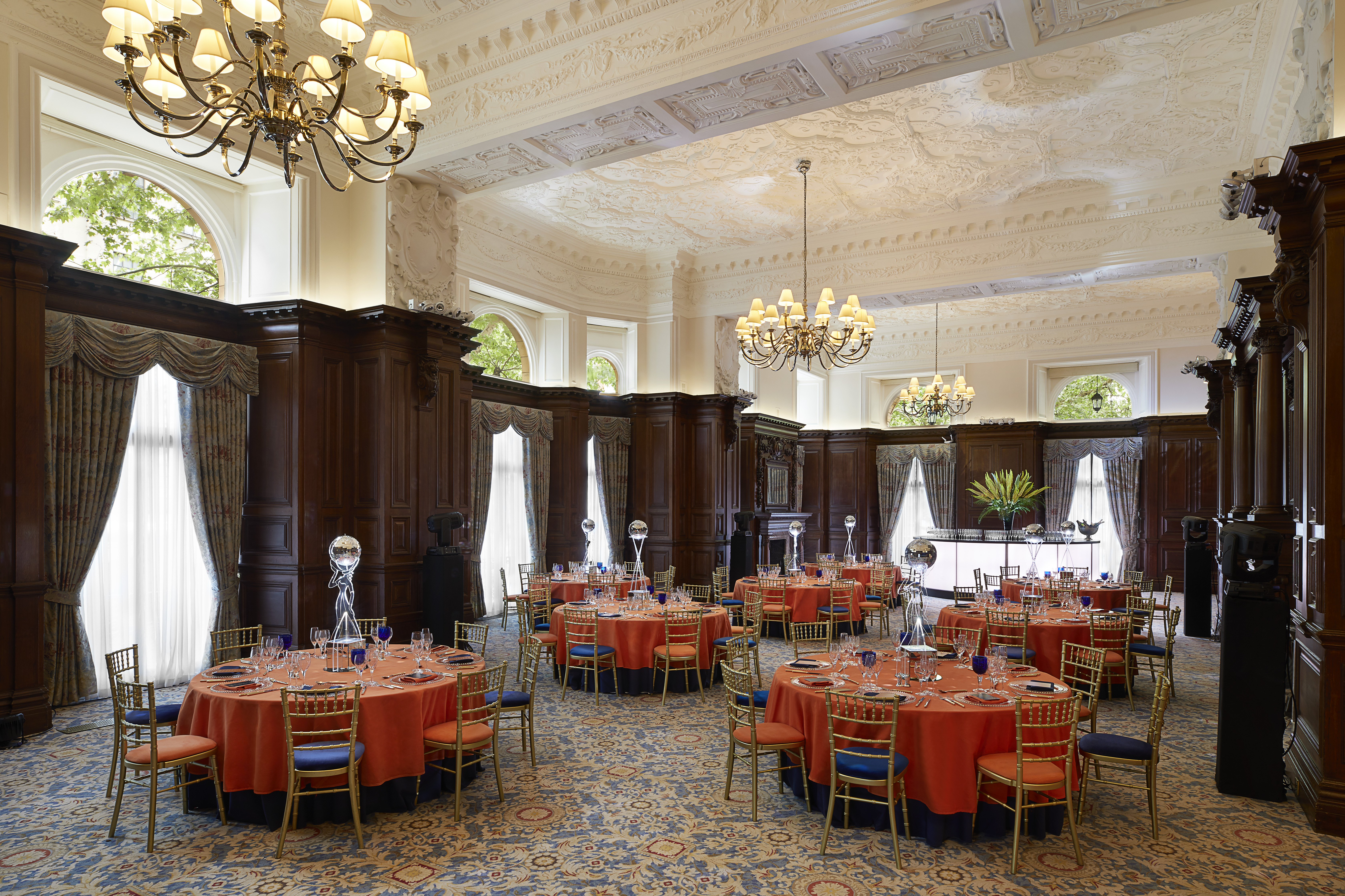 Elegant event space in The Landmark London with orange linens, ideal for corporate gatherings.