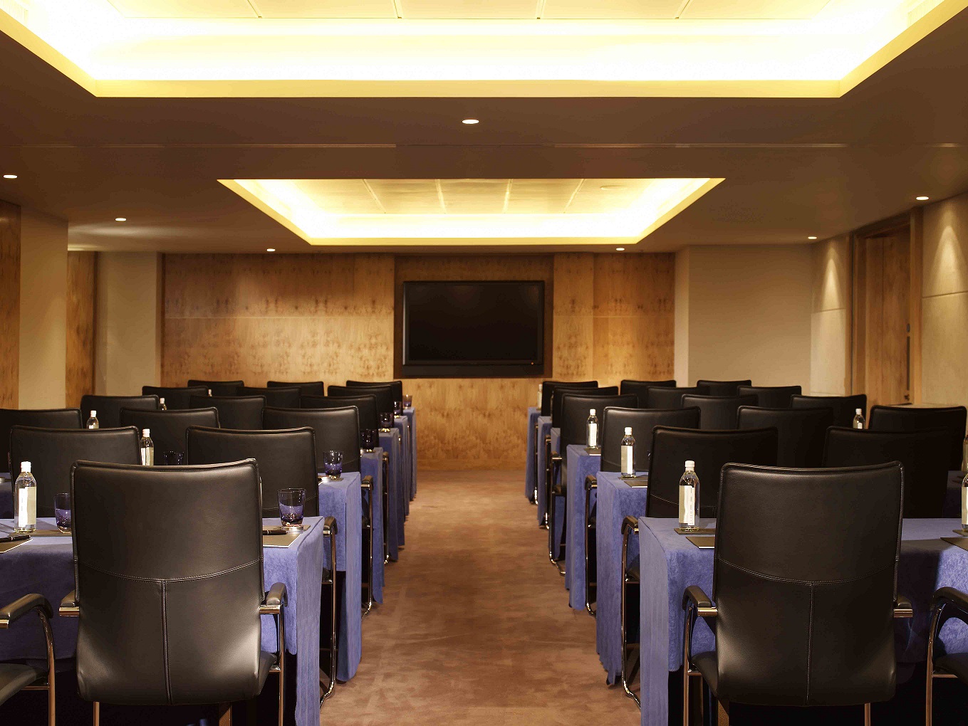 Modern meeting room with black chairs and blue table covers at The Landmark London.