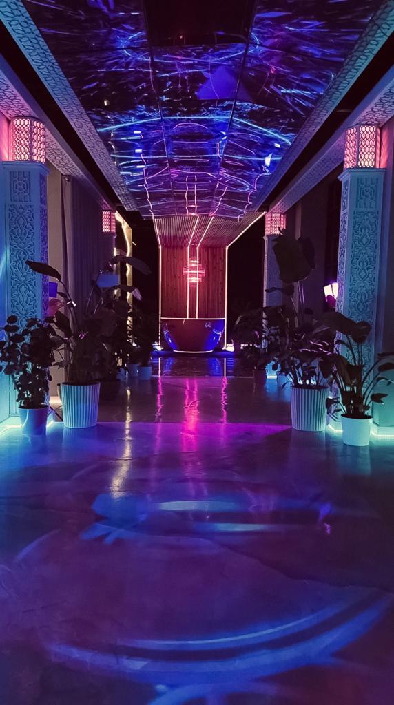 Stylish event space in The Room Digital Gallery with vibrant lighting and greenery.