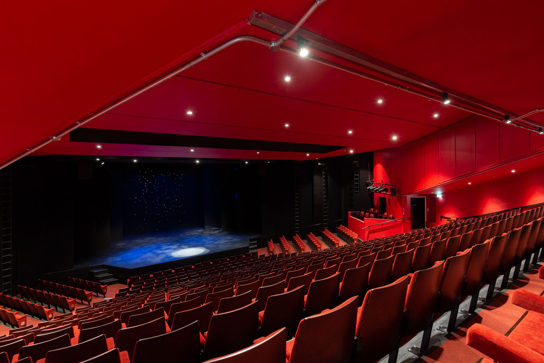 Modern Mercury Theatre with vibrant red decor, ideal for performances and conferences.