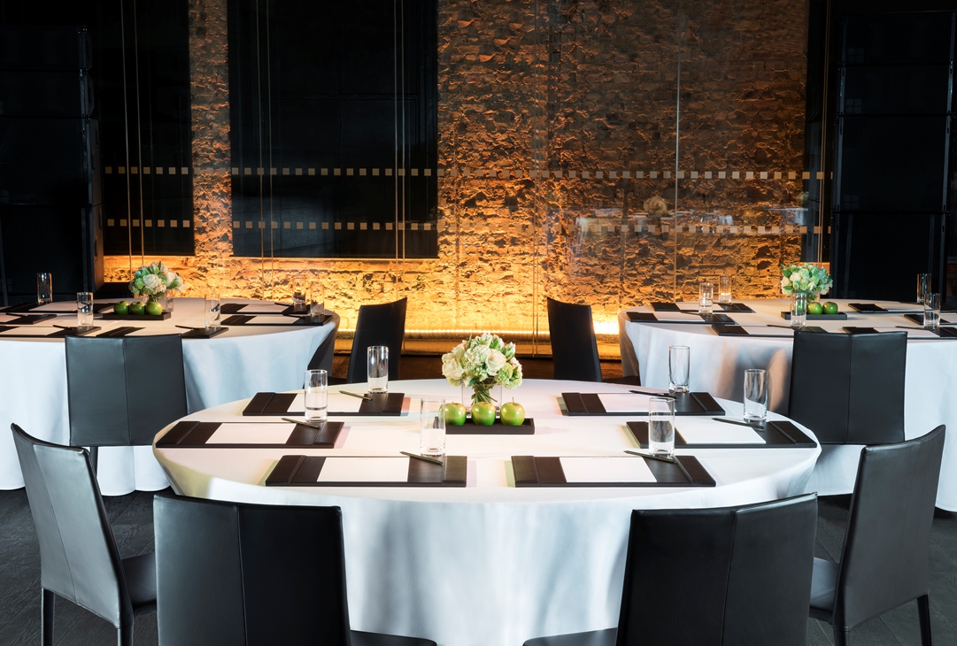 Sophisticated event setup with round tables in The London EDITION basement for corporate meetings.