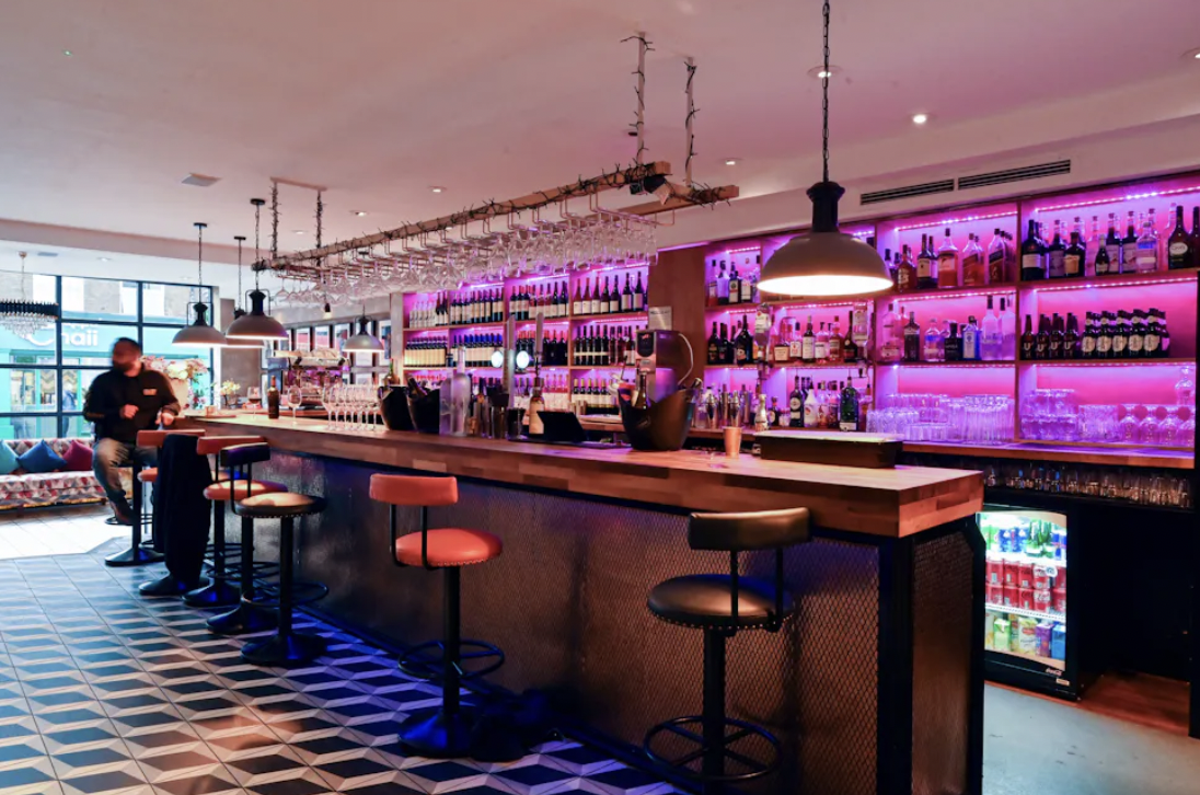 Private dining bar at Bombay Delight with vibrant purple lighting for networking events.