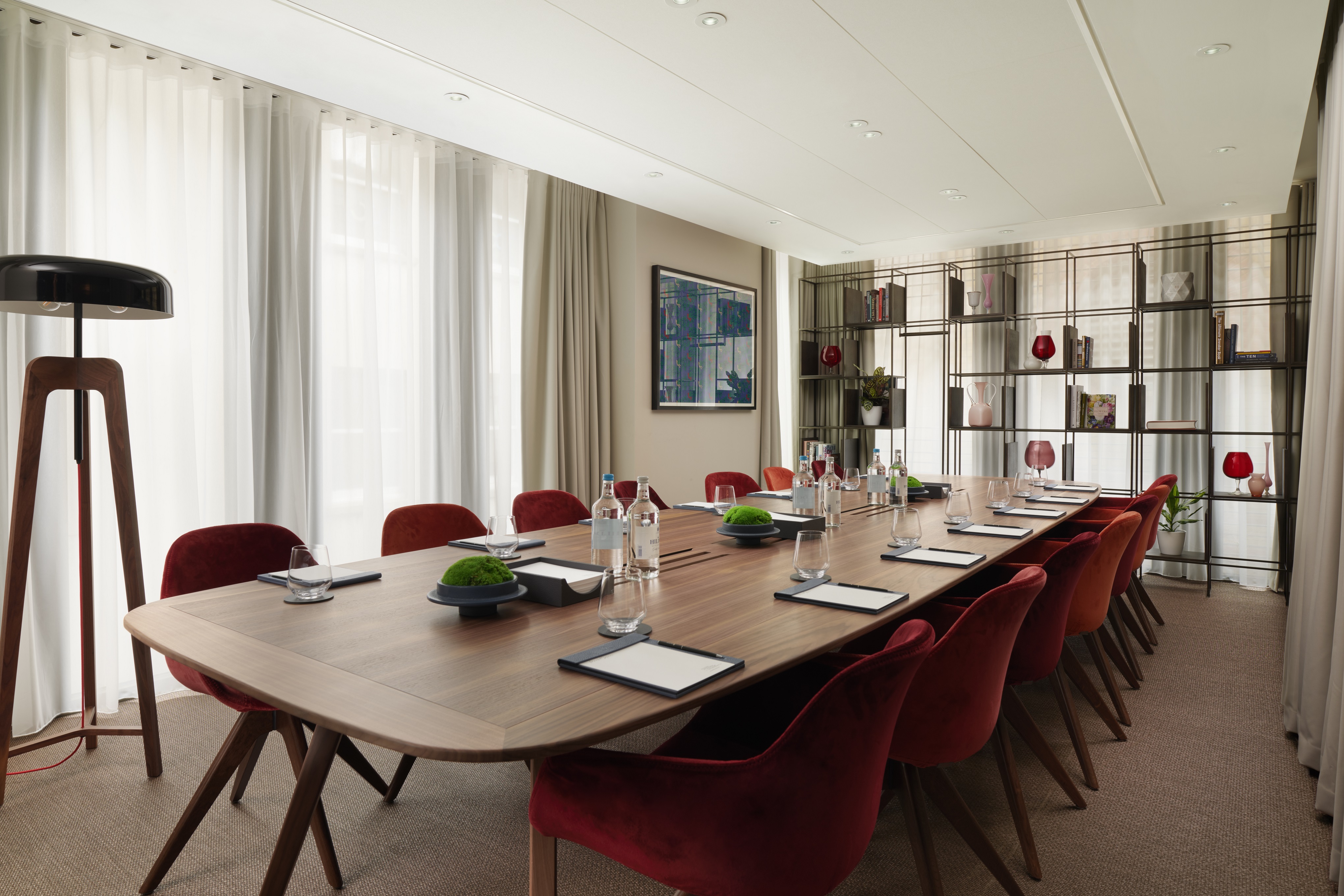 Modern meeting room in Pan Pacific London with elegant wooden table and plush red chairs.