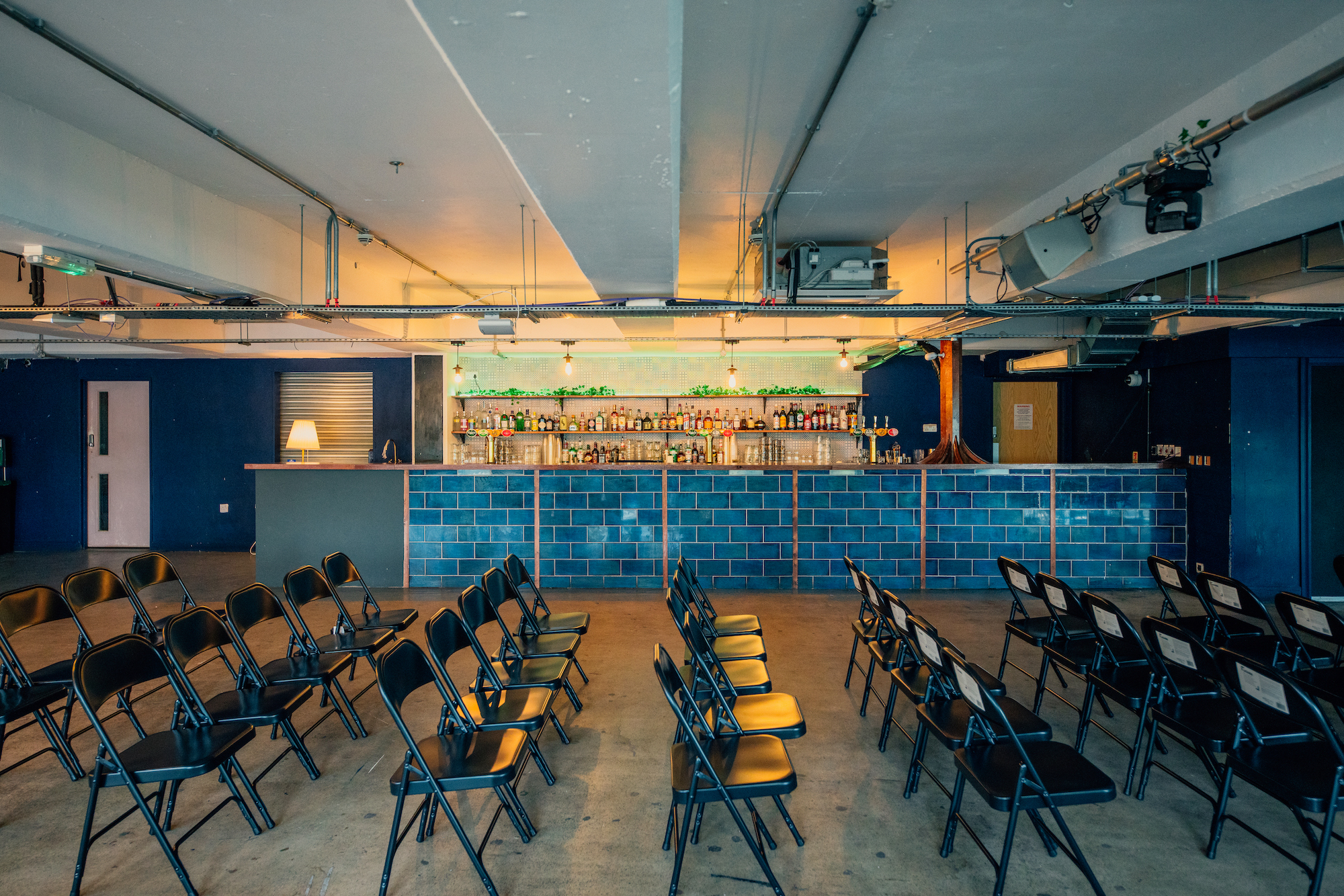 Versatile event space in Peckham Levels with sleek bar and black folding chairs.