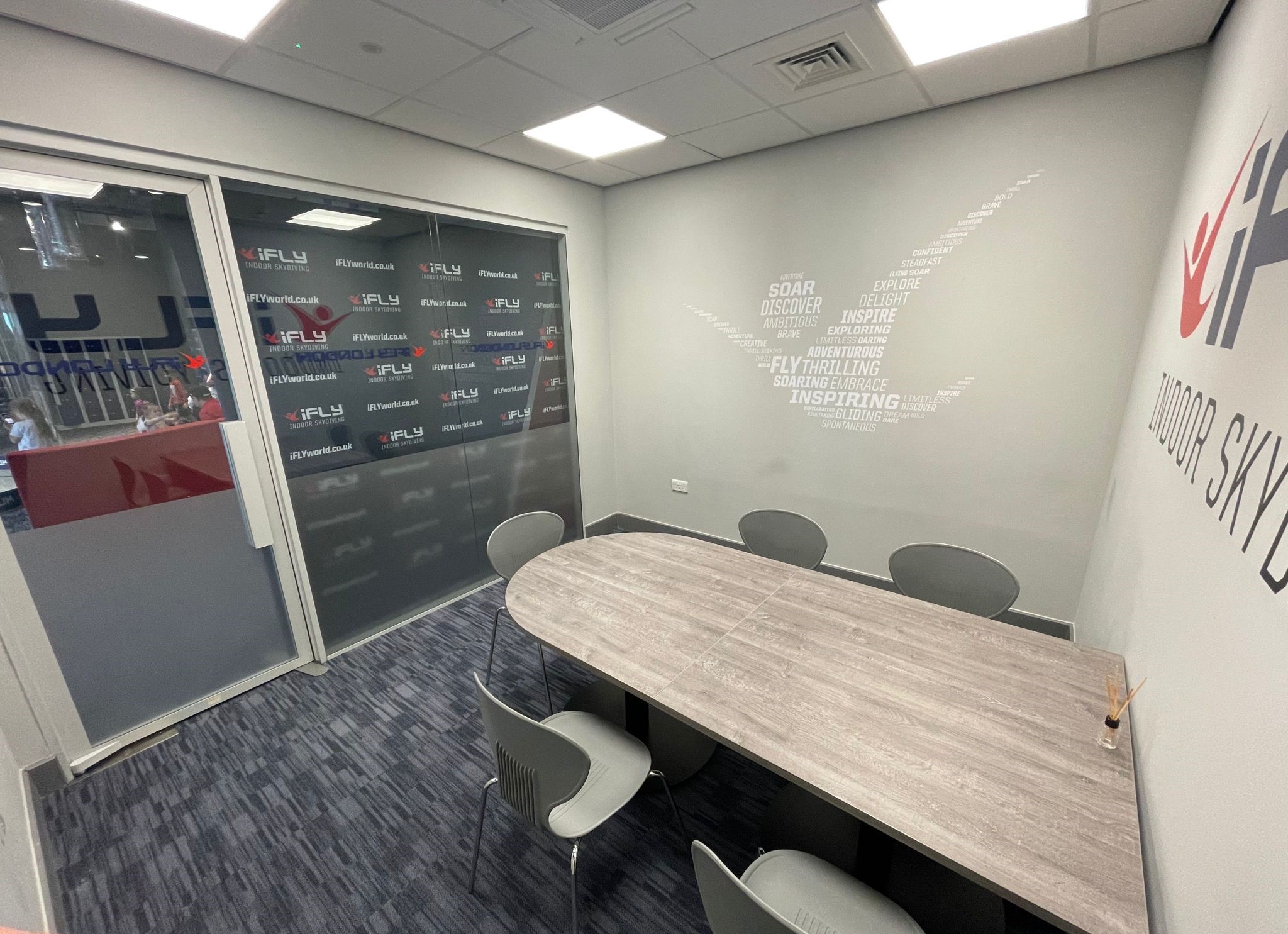 Modern meeting room with oval table at iFLY Indoor Skydiving, ideal for corporate events.