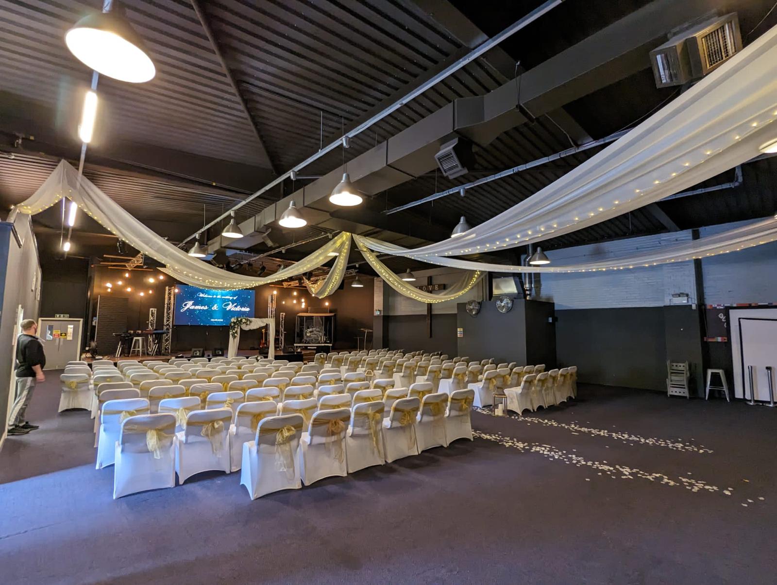 Large Function Hall at Victory Outreach Manchester, elegant wedding venue with chairs and lighting.