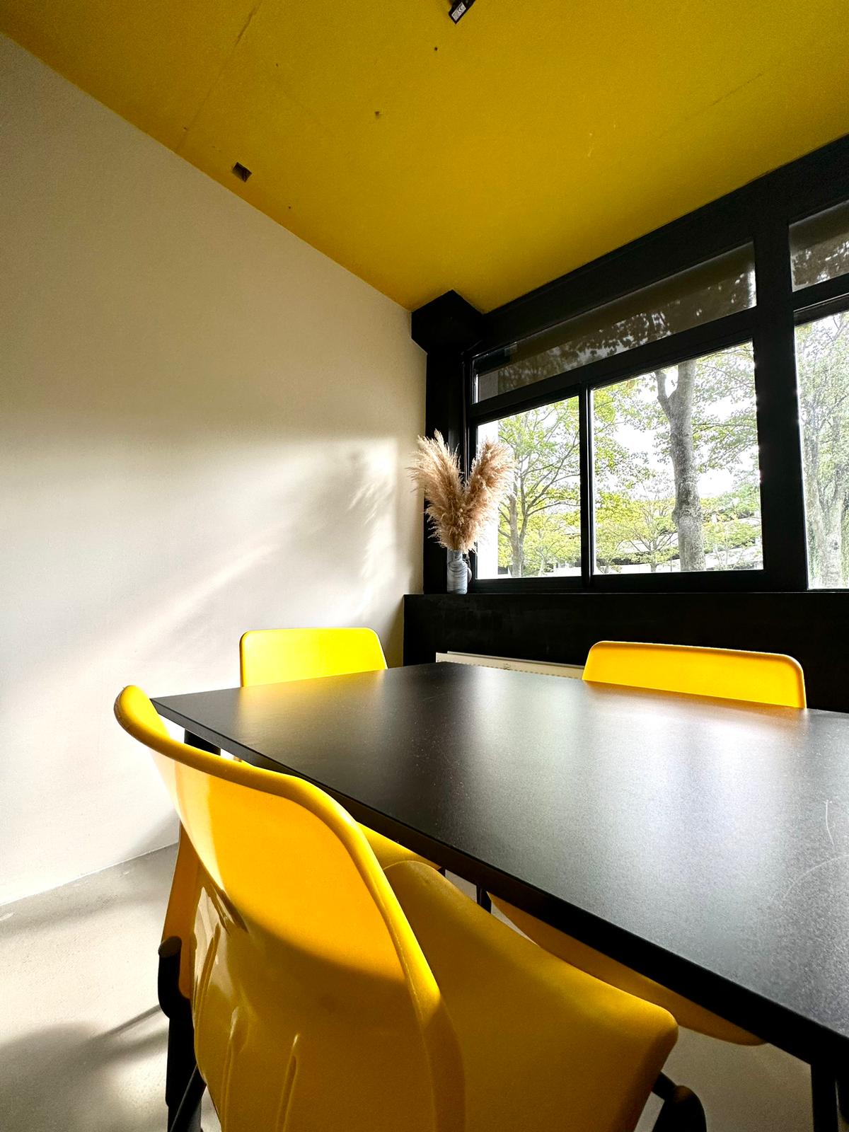 Modern meeting space with black table and yellow chairs in Urban Hotel TGS.