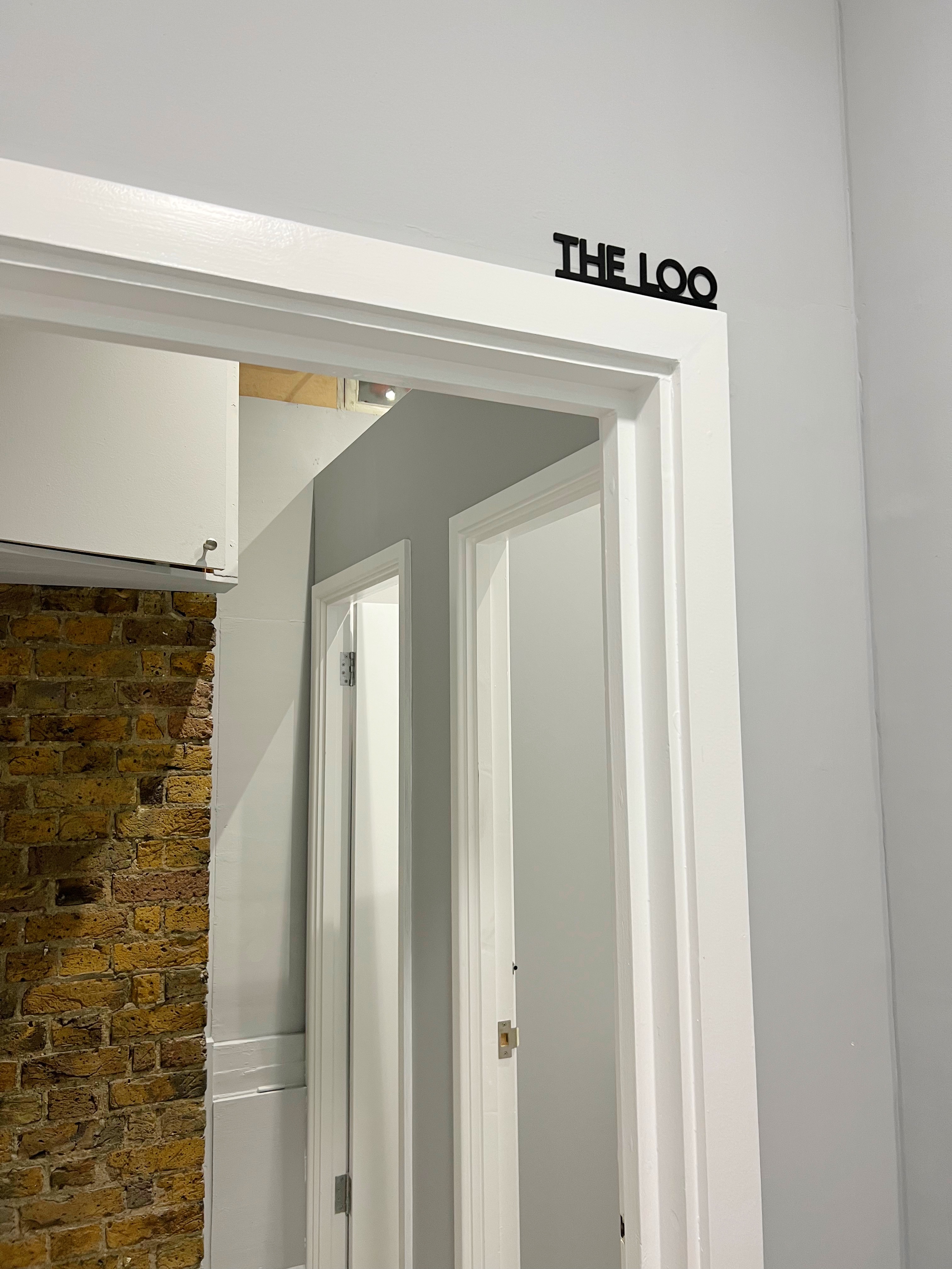 Modern corridor in ARC STUDIOS, featuring sleek white walls and exposed brick for events.